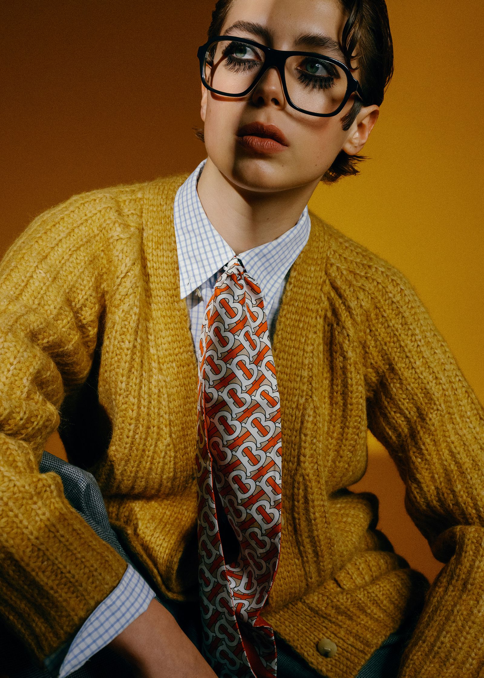 a young man wearing glasses and a yellow cardigan