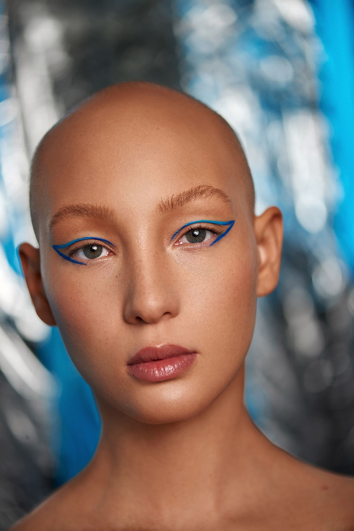 a woman with a bald head and blue eye makeup