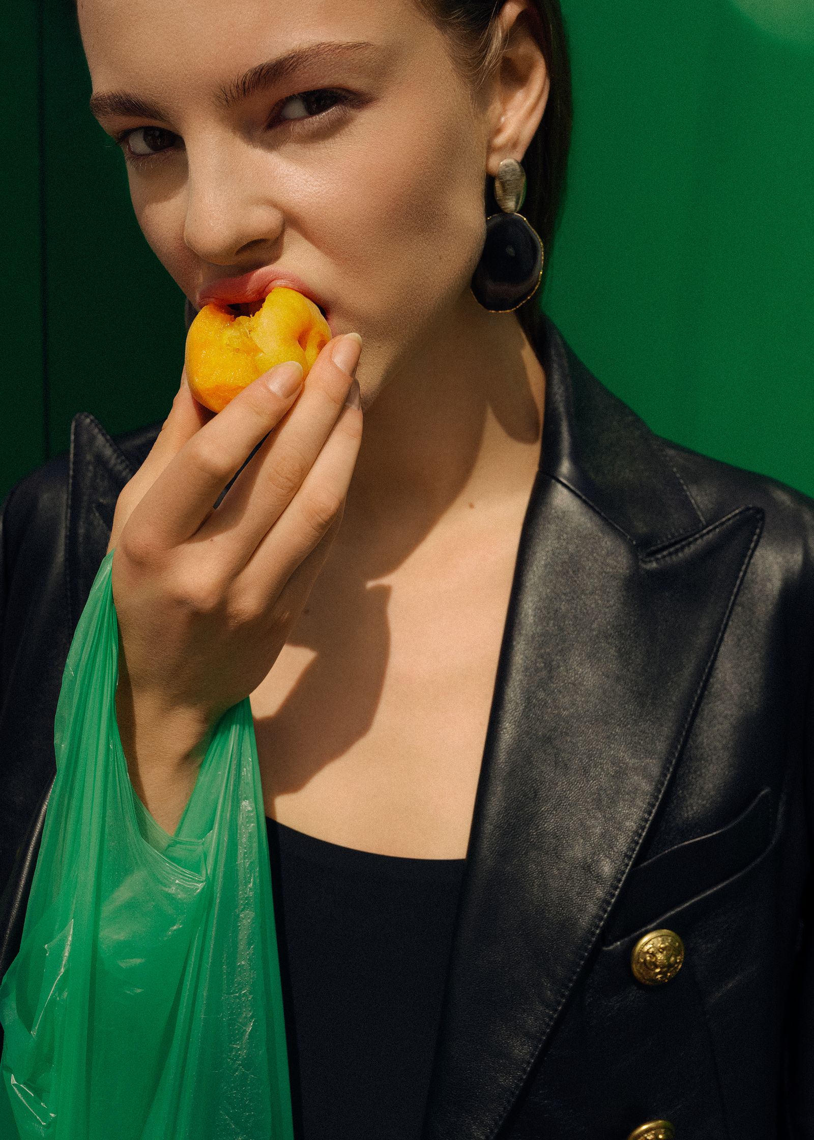 a woman is eating a peach in a green bag