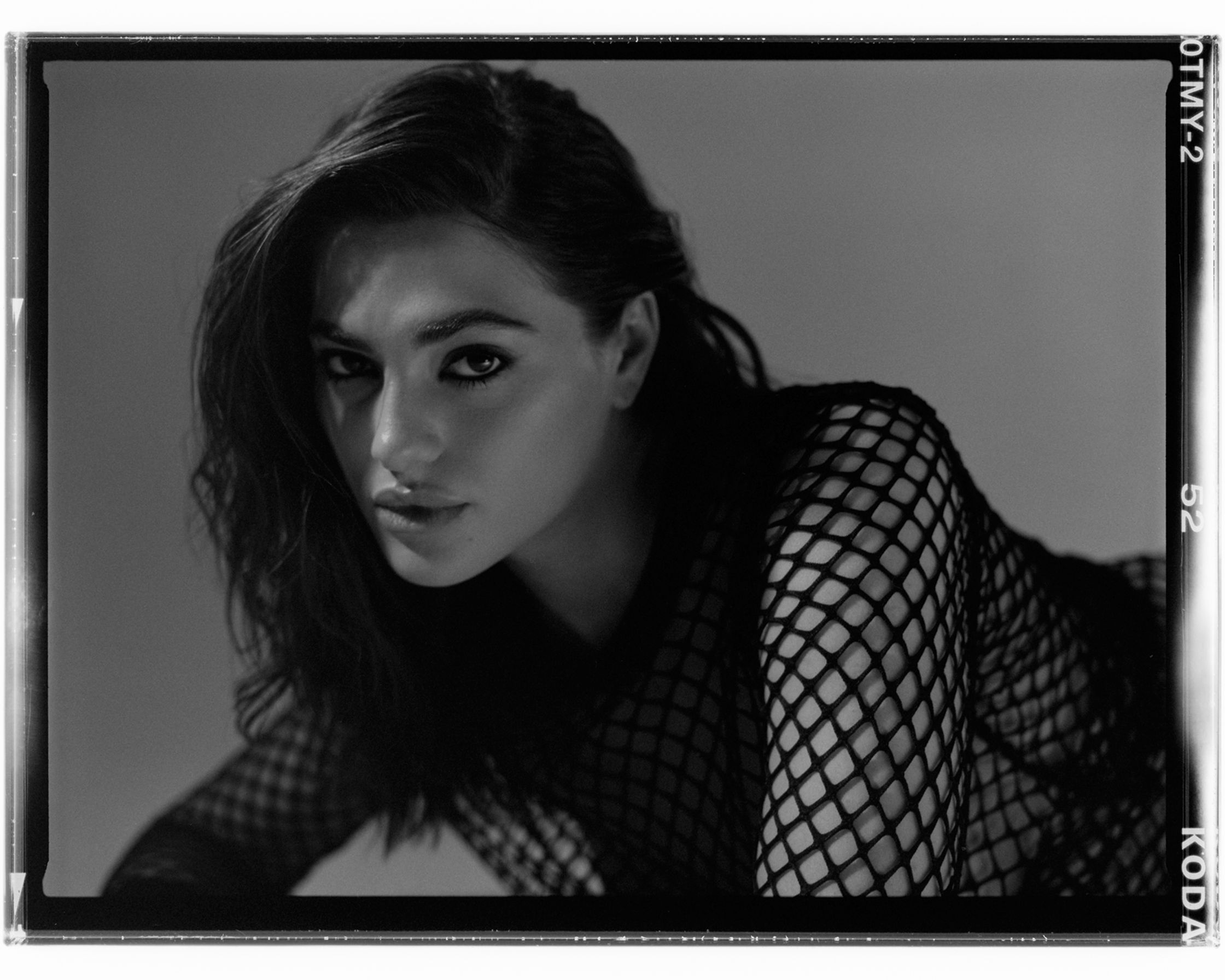 a black and white photo of a woman in a fishnet top
