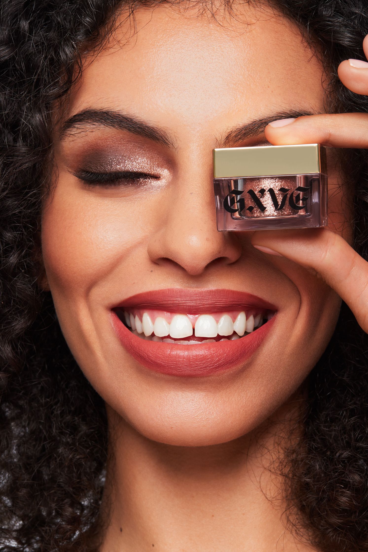 a woman is holding up a box of lipgloss