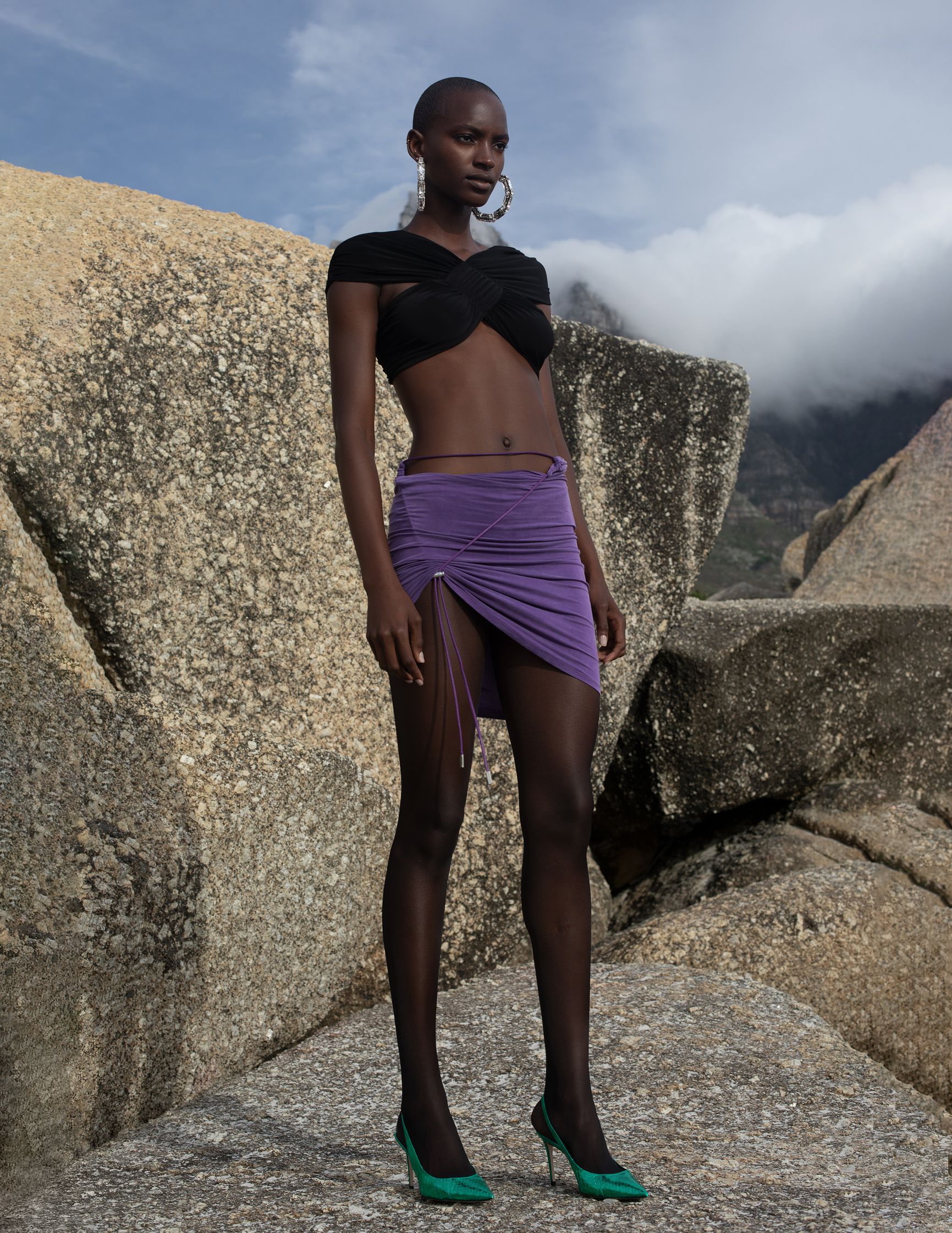 a woman in a purple skirt standing on a rock