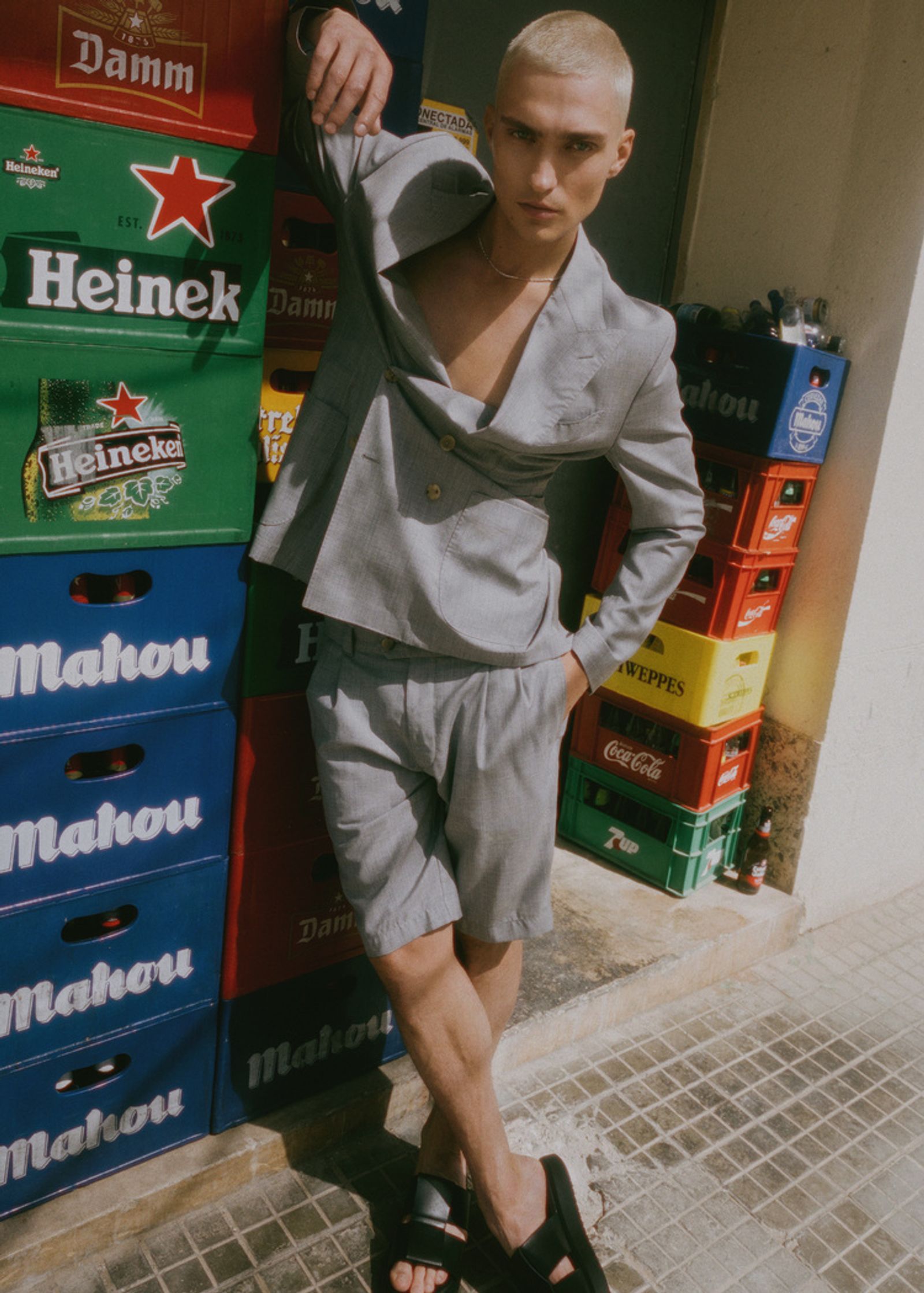 a man in a grey suit leaning against a box of cans