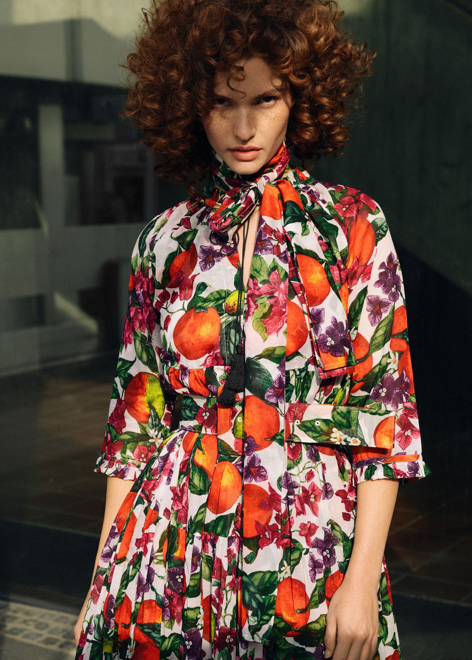 a woman with curly hair in a colorful floral dress