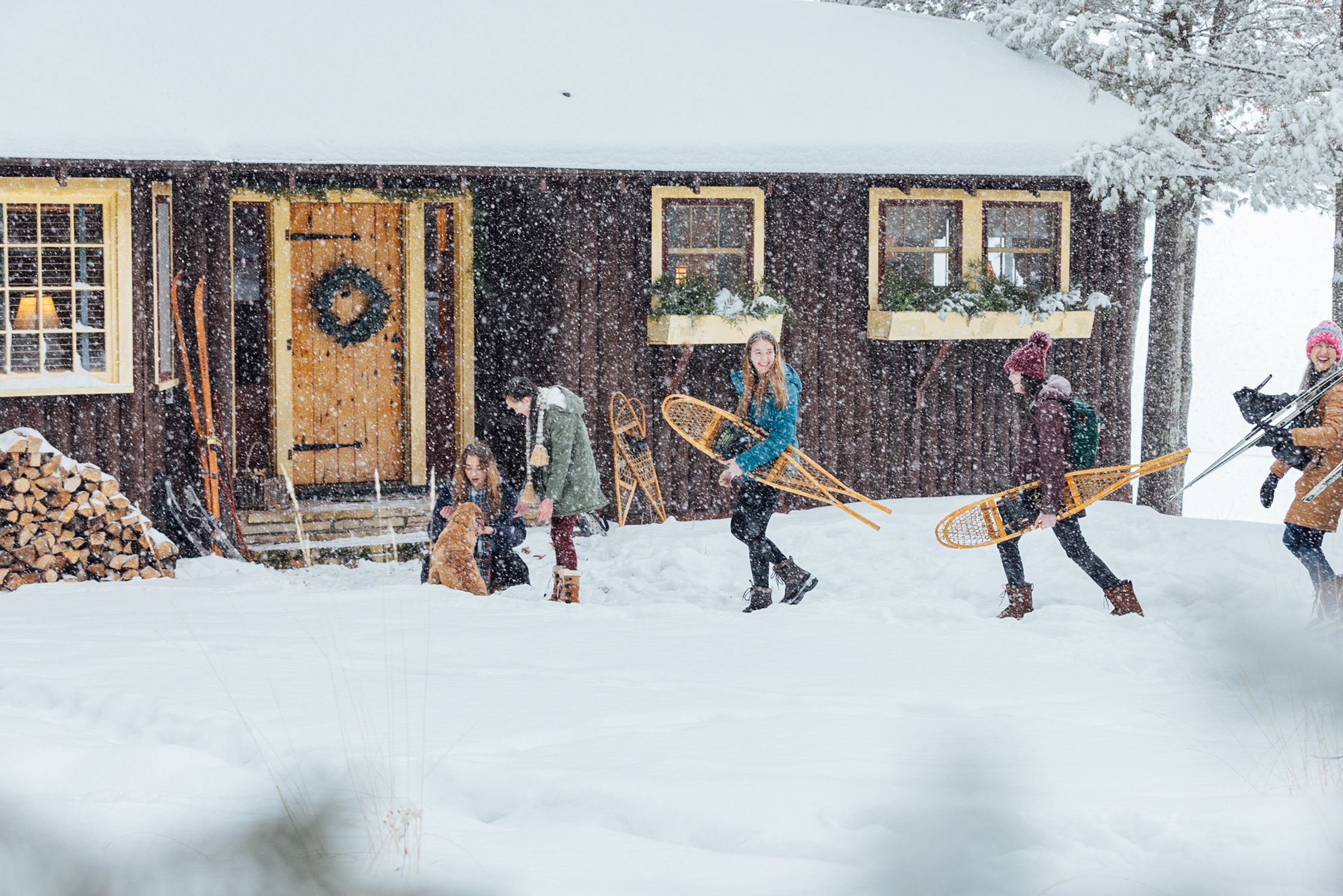 a group of people walking in the snow near a cabin