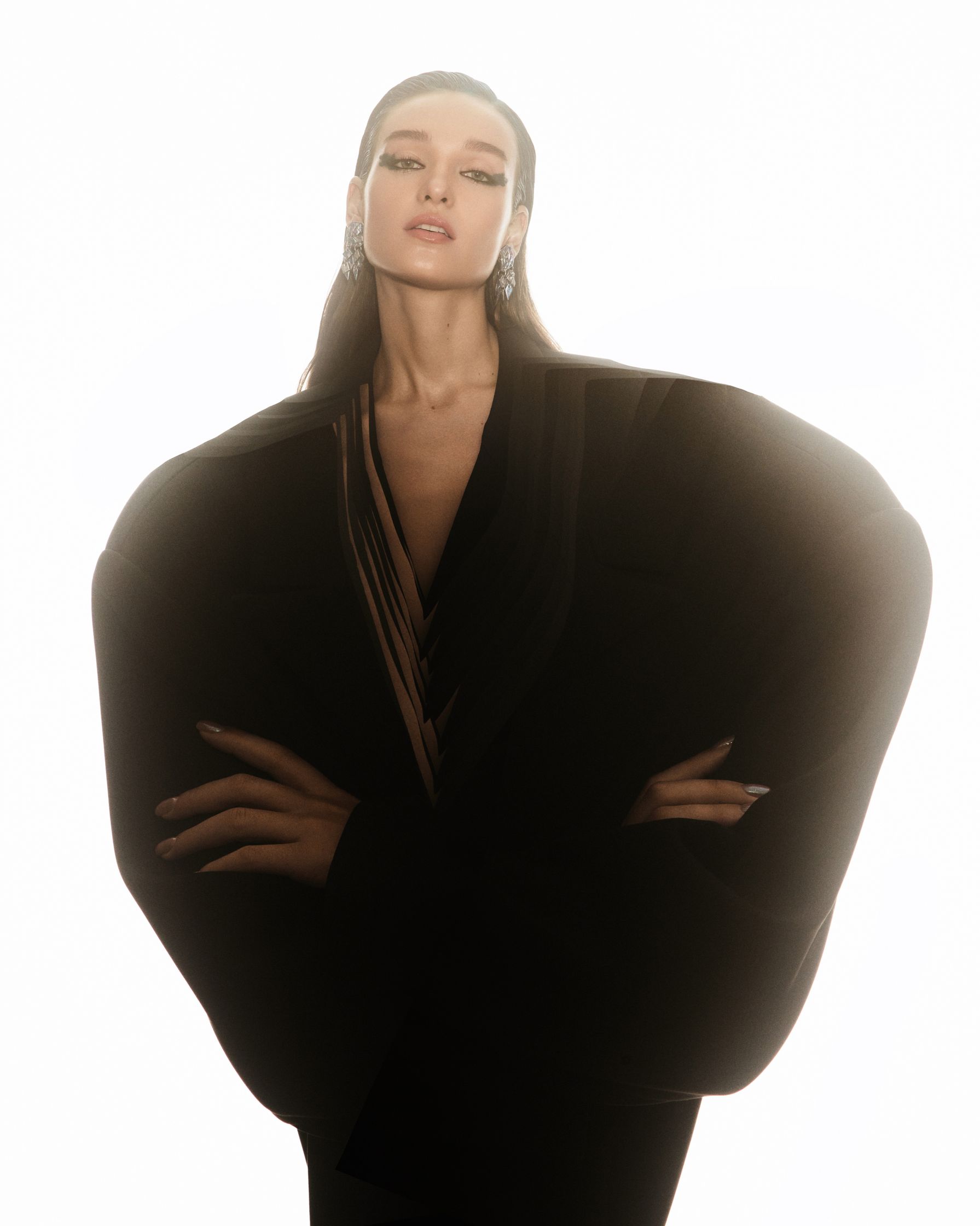 a woman in a black coat is posing in front of a white background