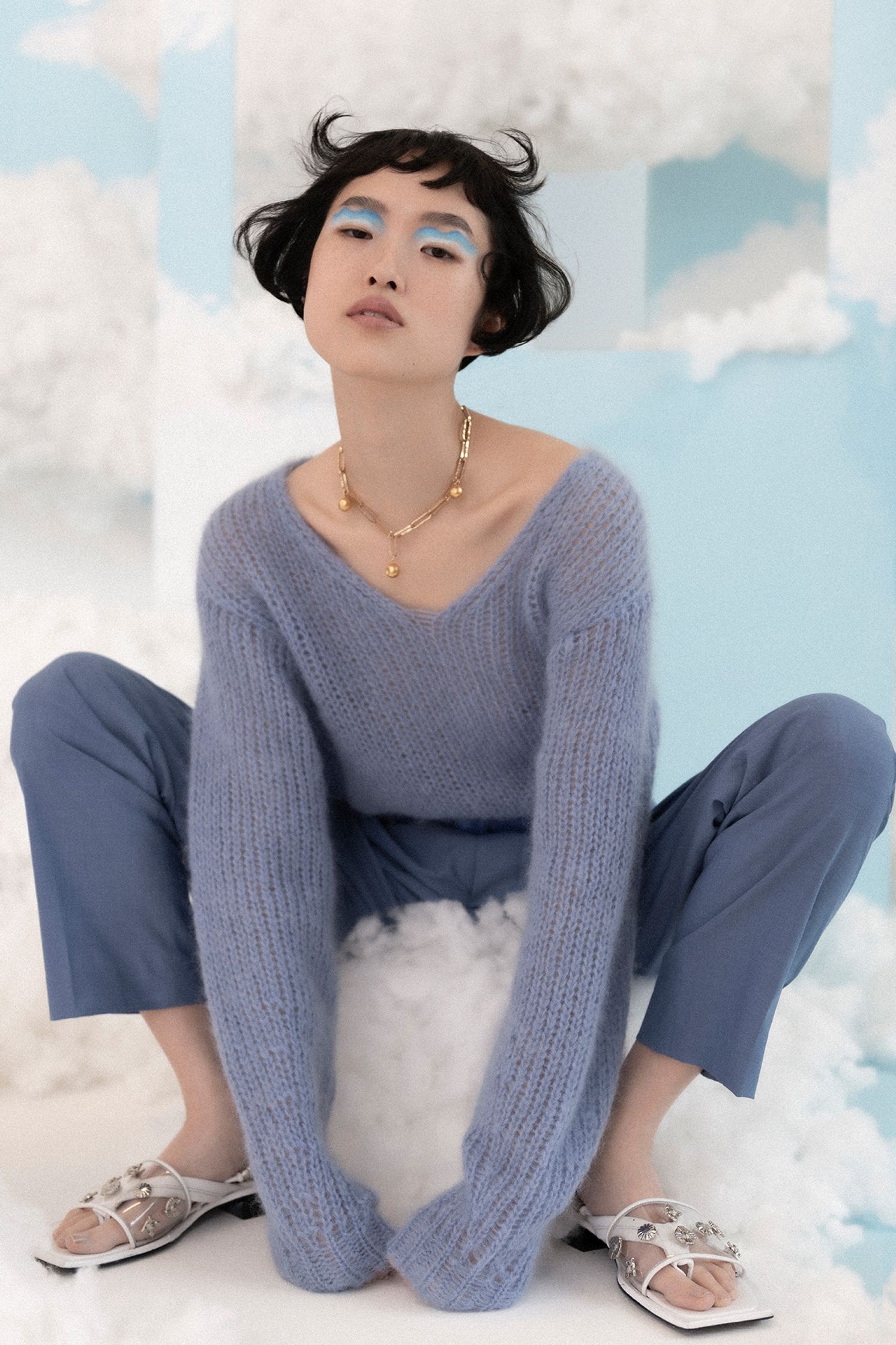 a woman in a blue sweater sitting on a cloud
