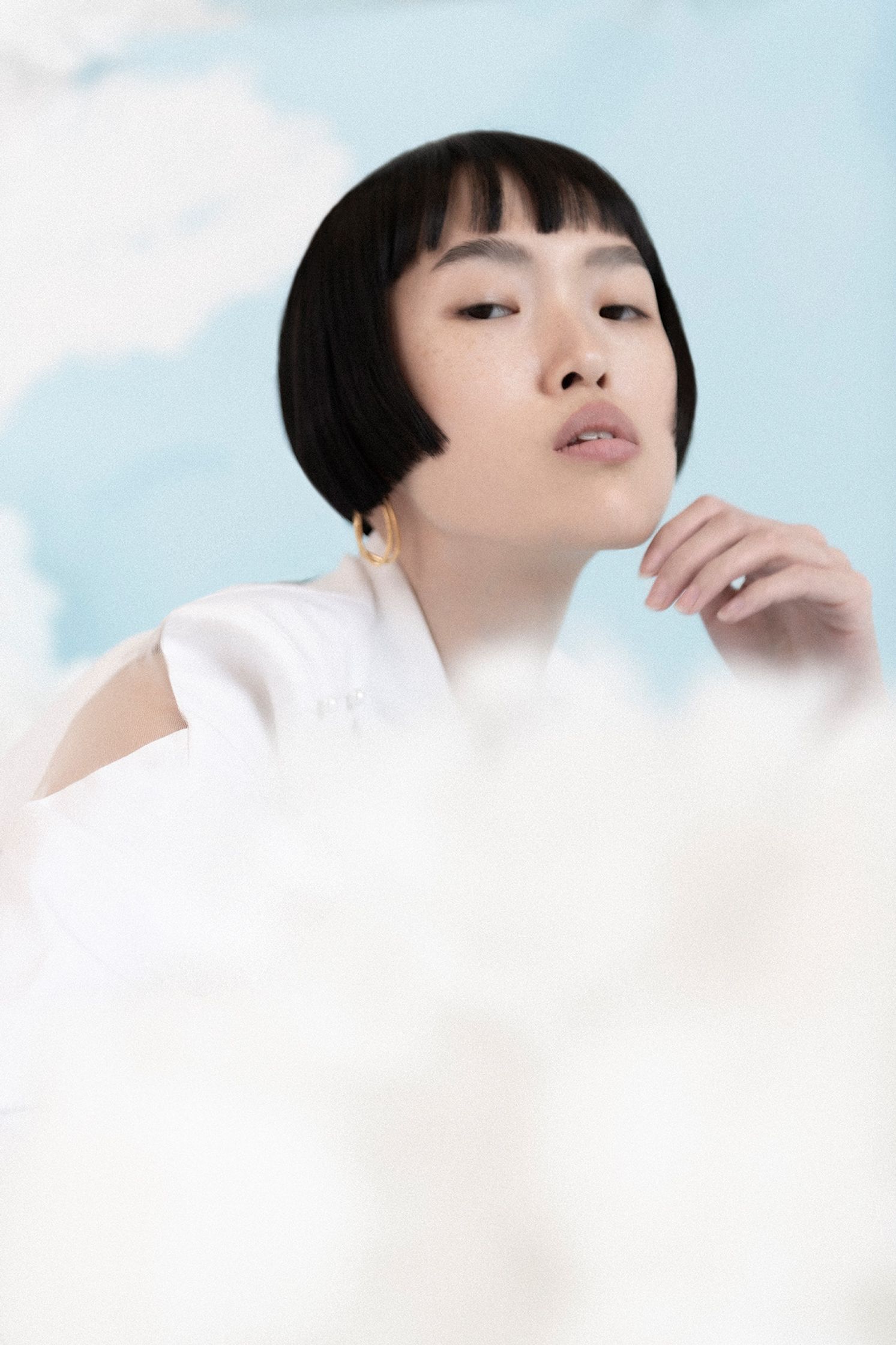 a young asian woman posing in front of clouds