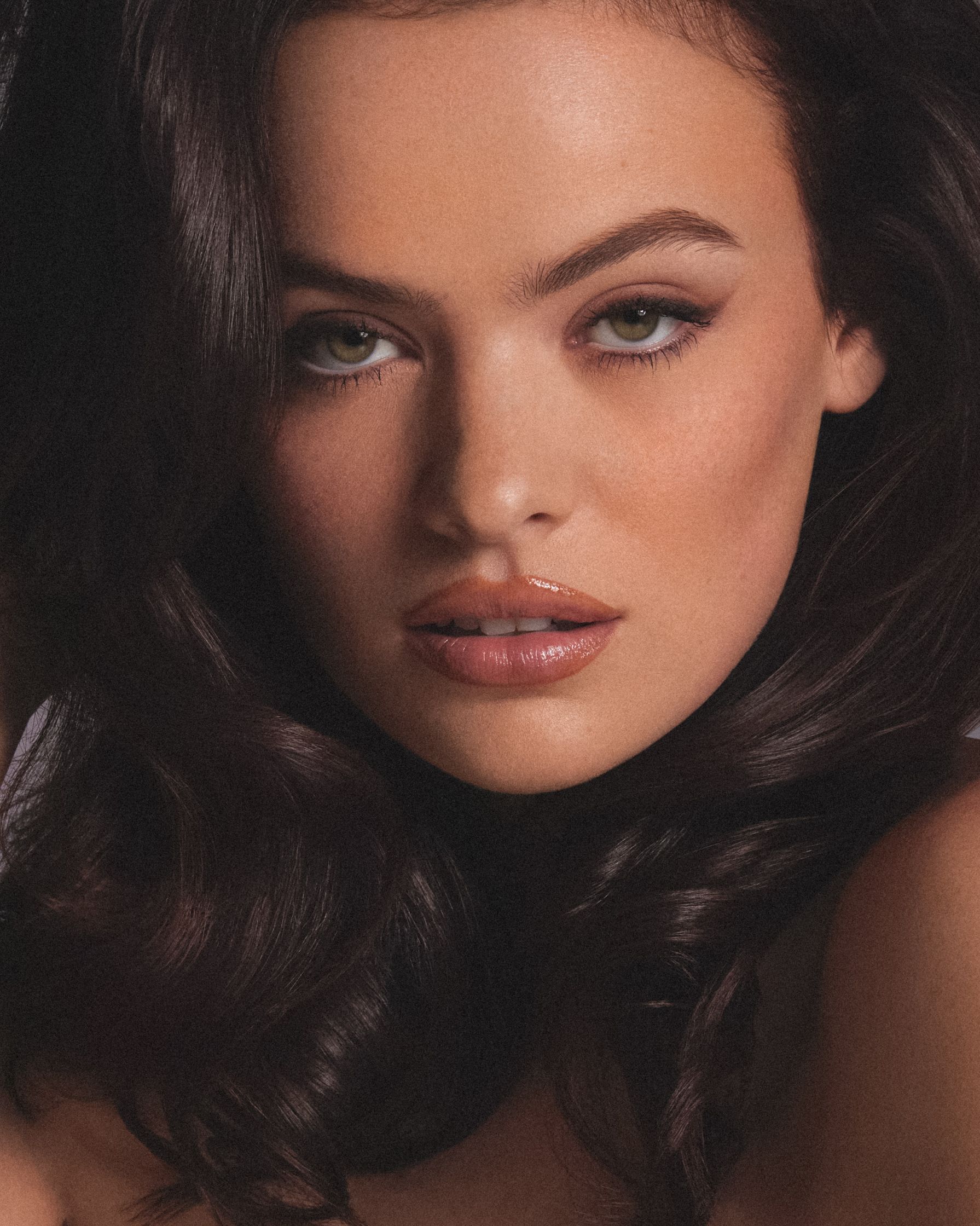 a woman with long dark hair posing for a magazine