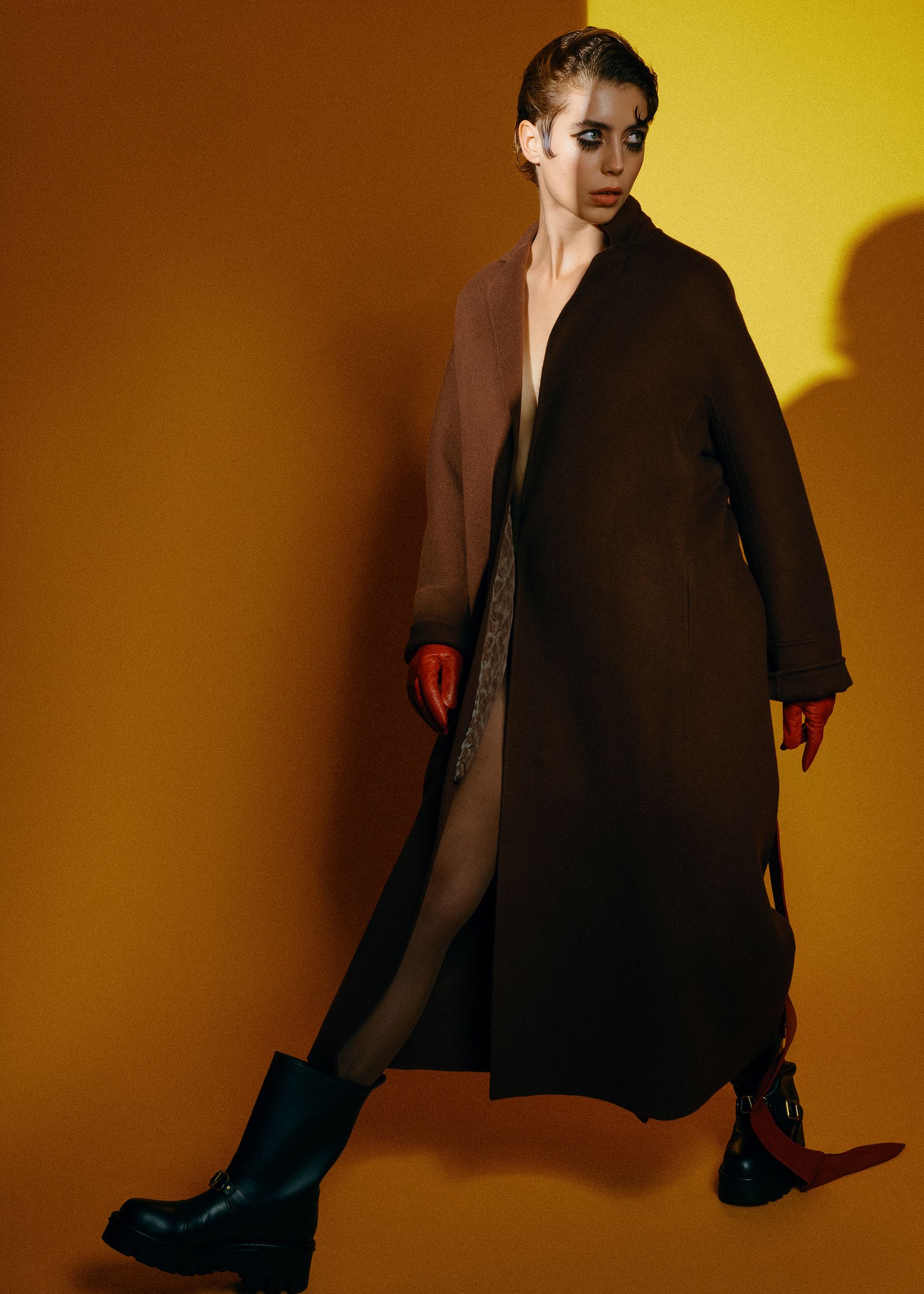 a woman in a brown coat and red boots