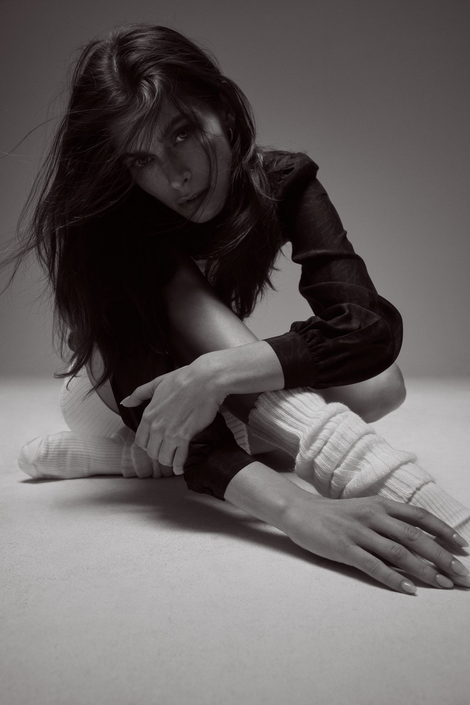 a black and white photo of a woman crouching on the floor