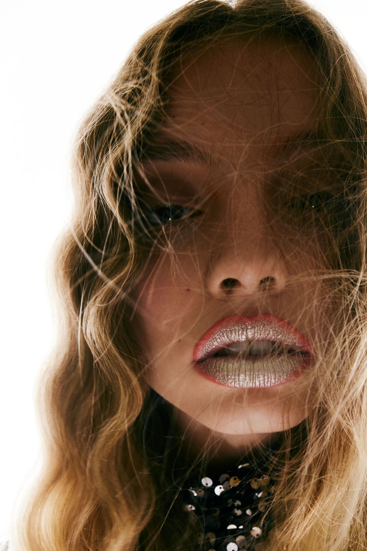 a woman with long wavy hair and silver lips