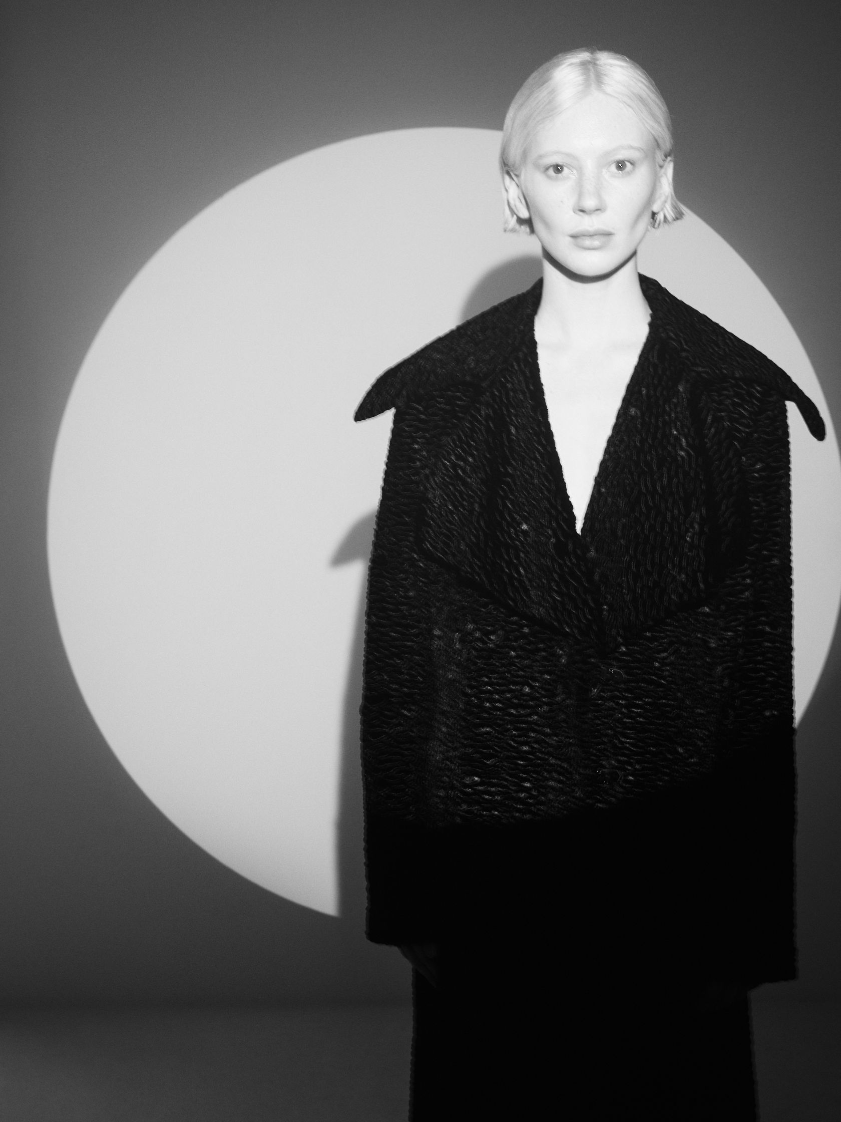 a black and white photo of a woman in a coat