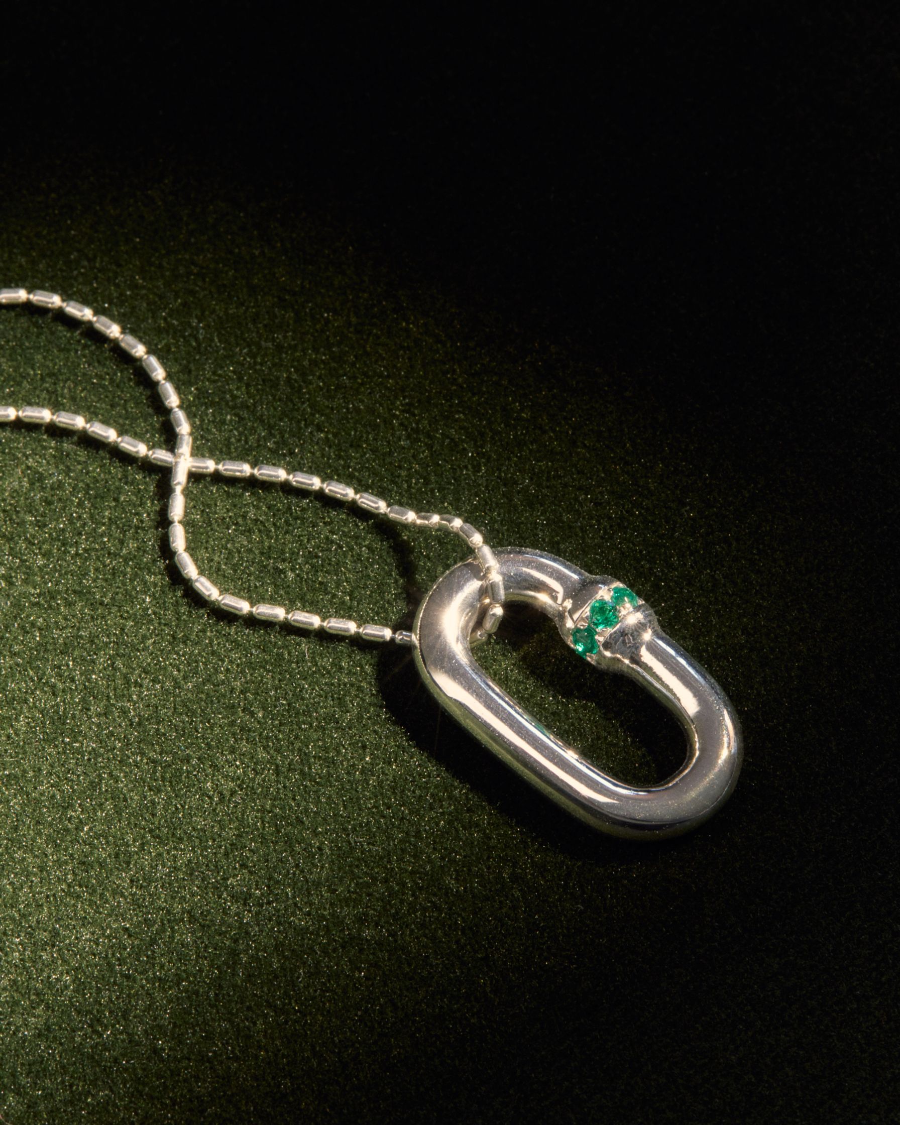 a silver necklace with an emerald on it