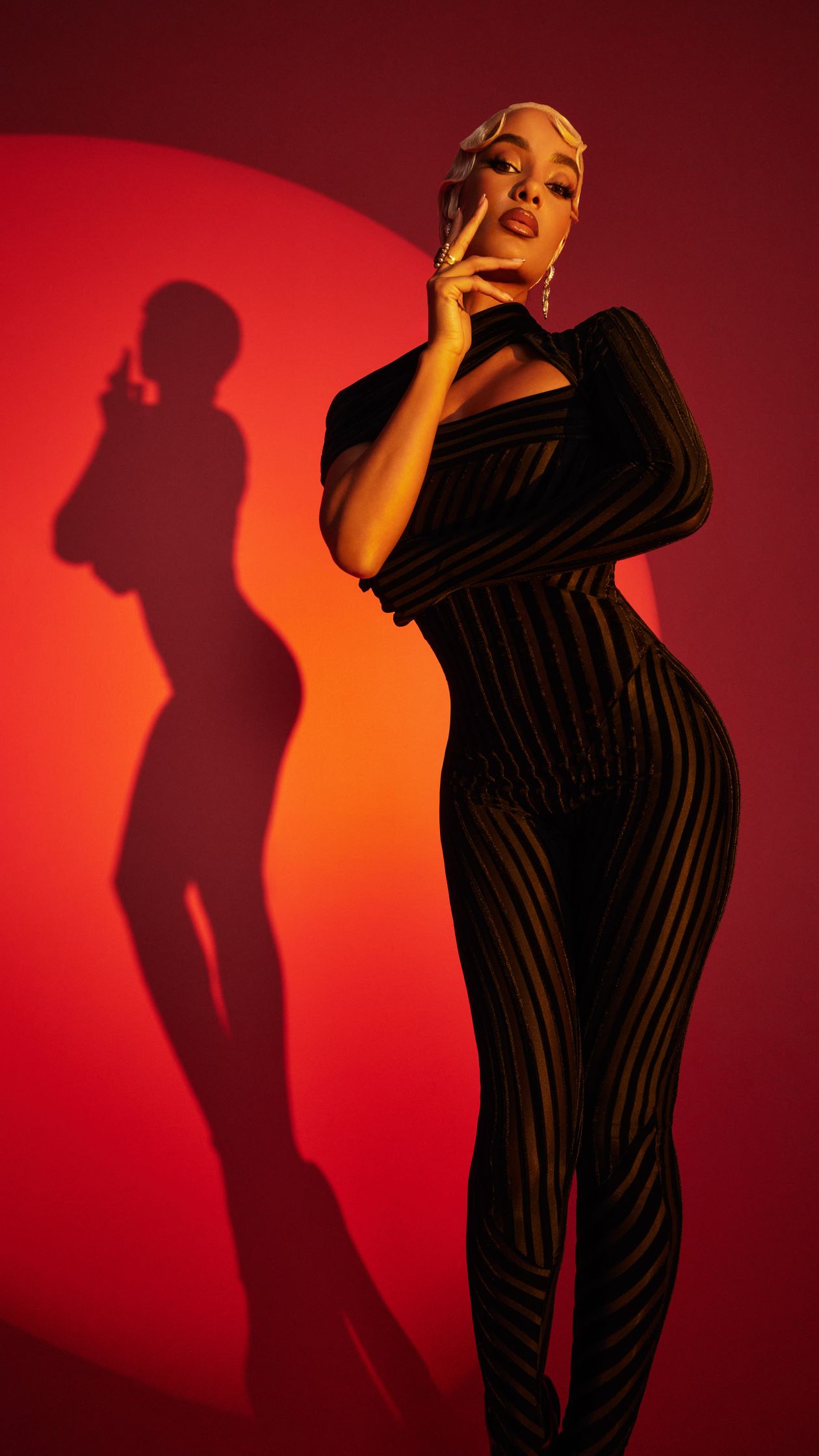 a woman in a striped jumpsuit posing in front of a red background