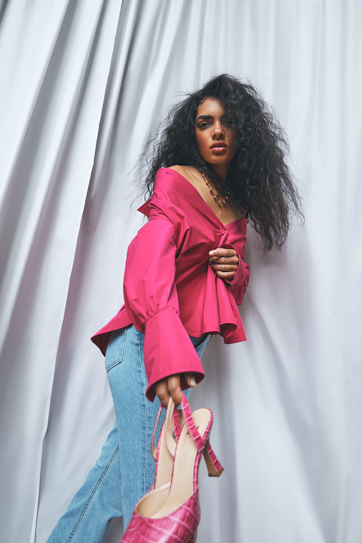 a woman in a pink top and jeans posing for a photo