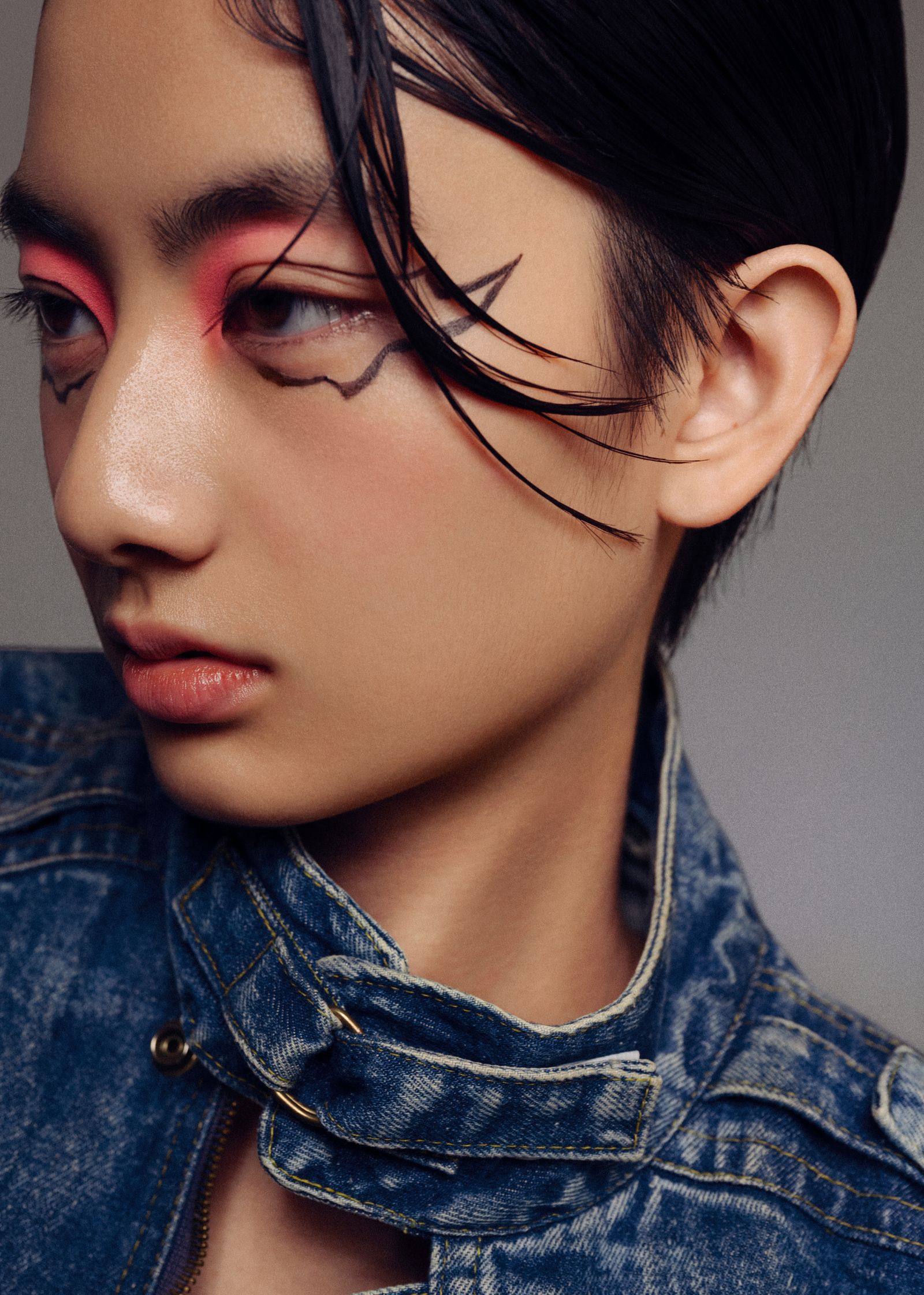 a woman wearing a denim jacket with pink eye makeup