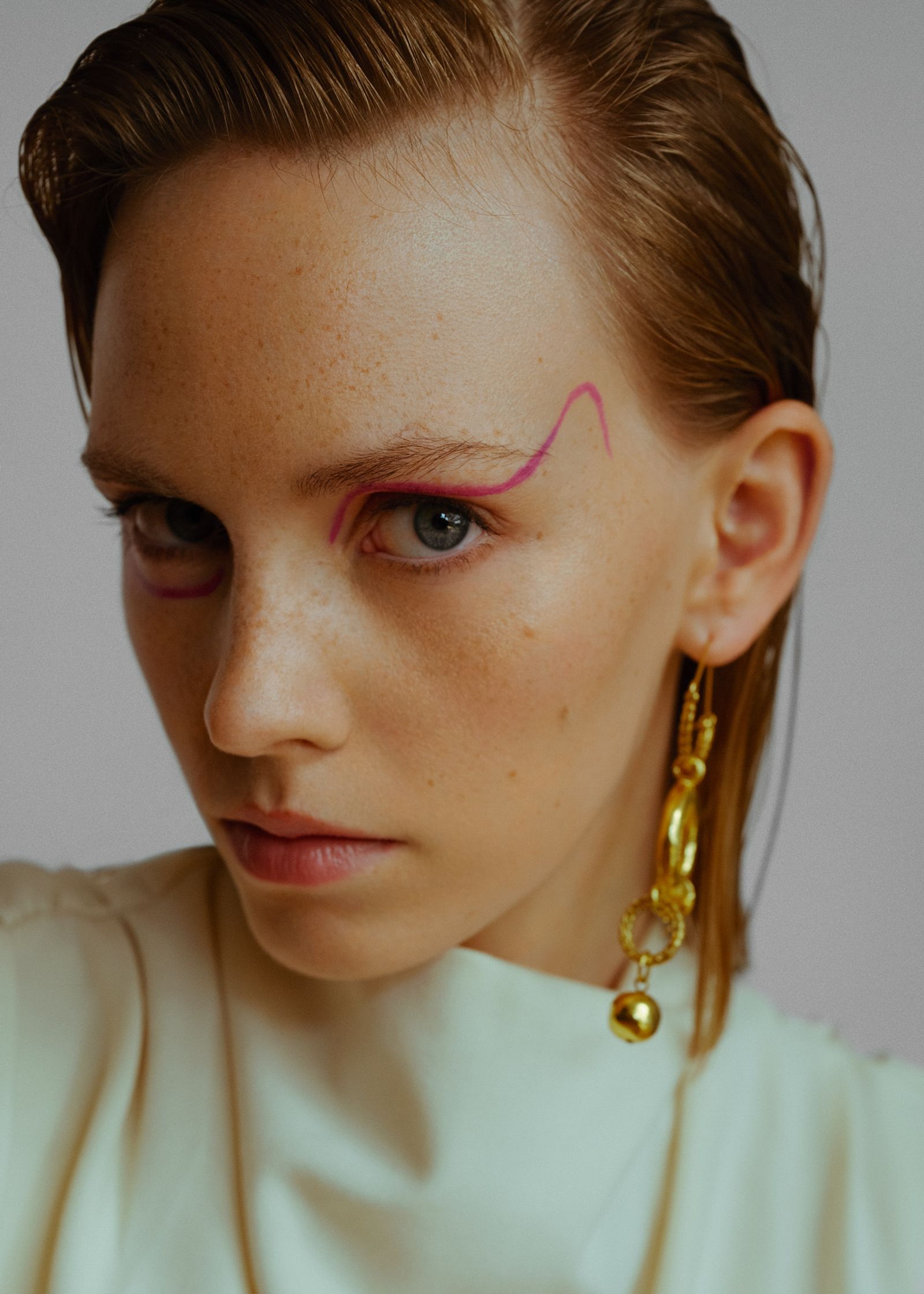a woman with a pink earring is posing for a magazine