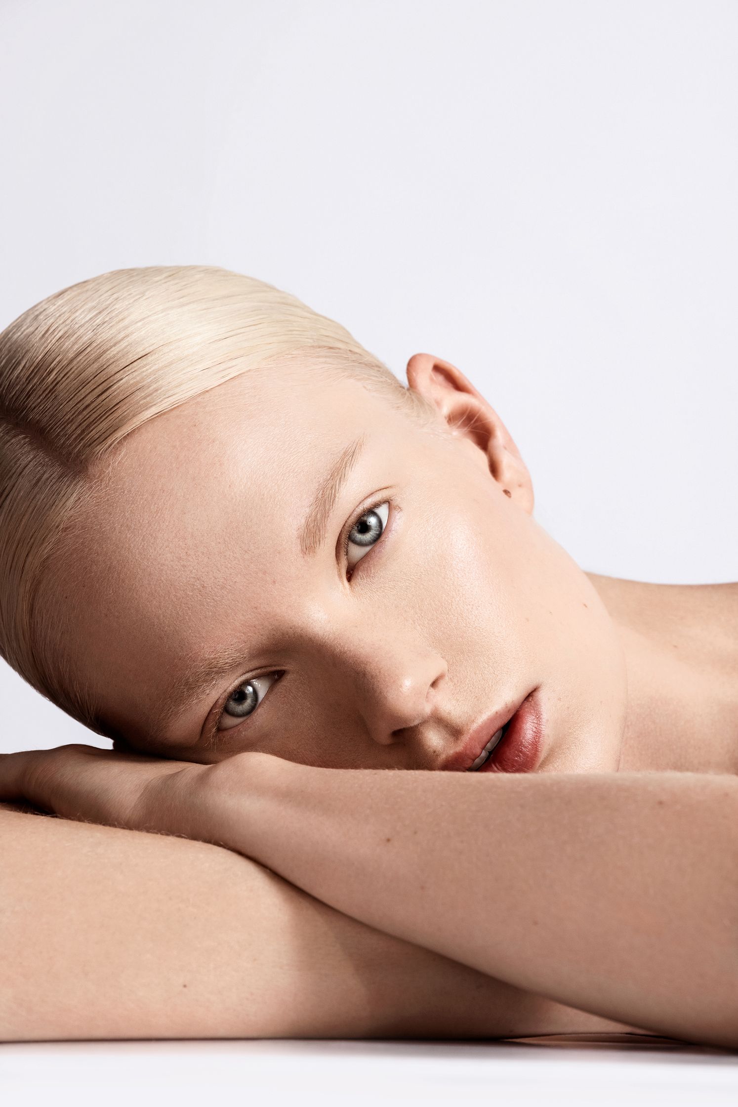 a woman with blond hair laying down on a white background
