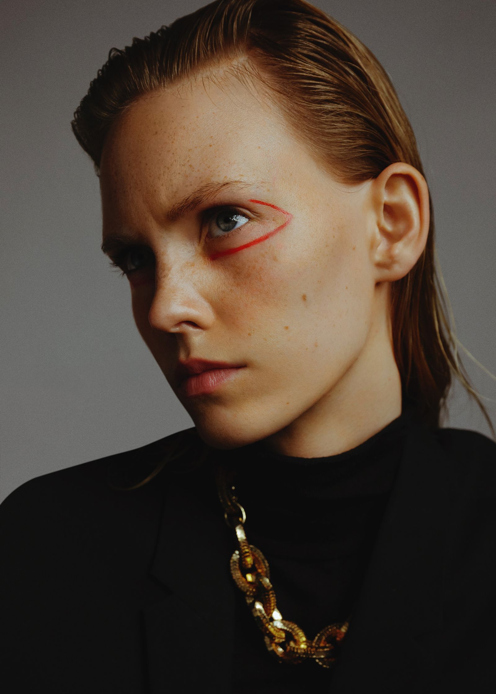 a woman wearing a black jacket and gold necklace