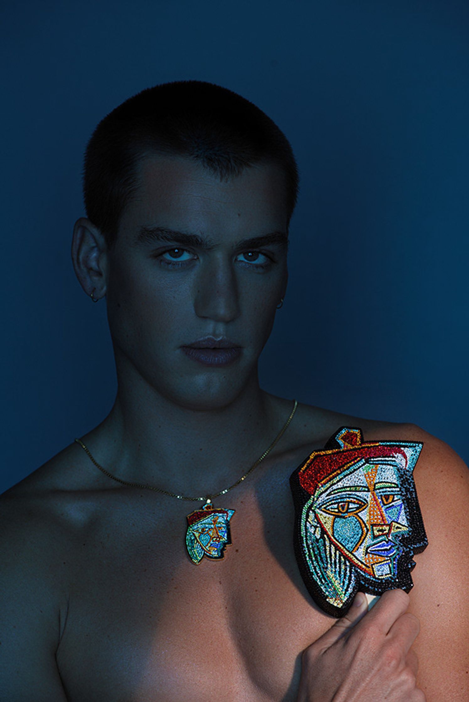 a shirtless man holding a necklace