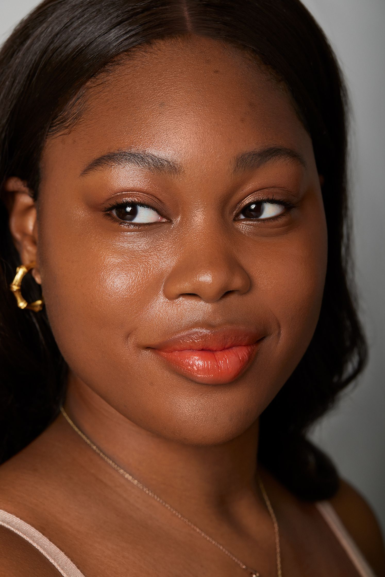 a young black woman wearing a top and earrings