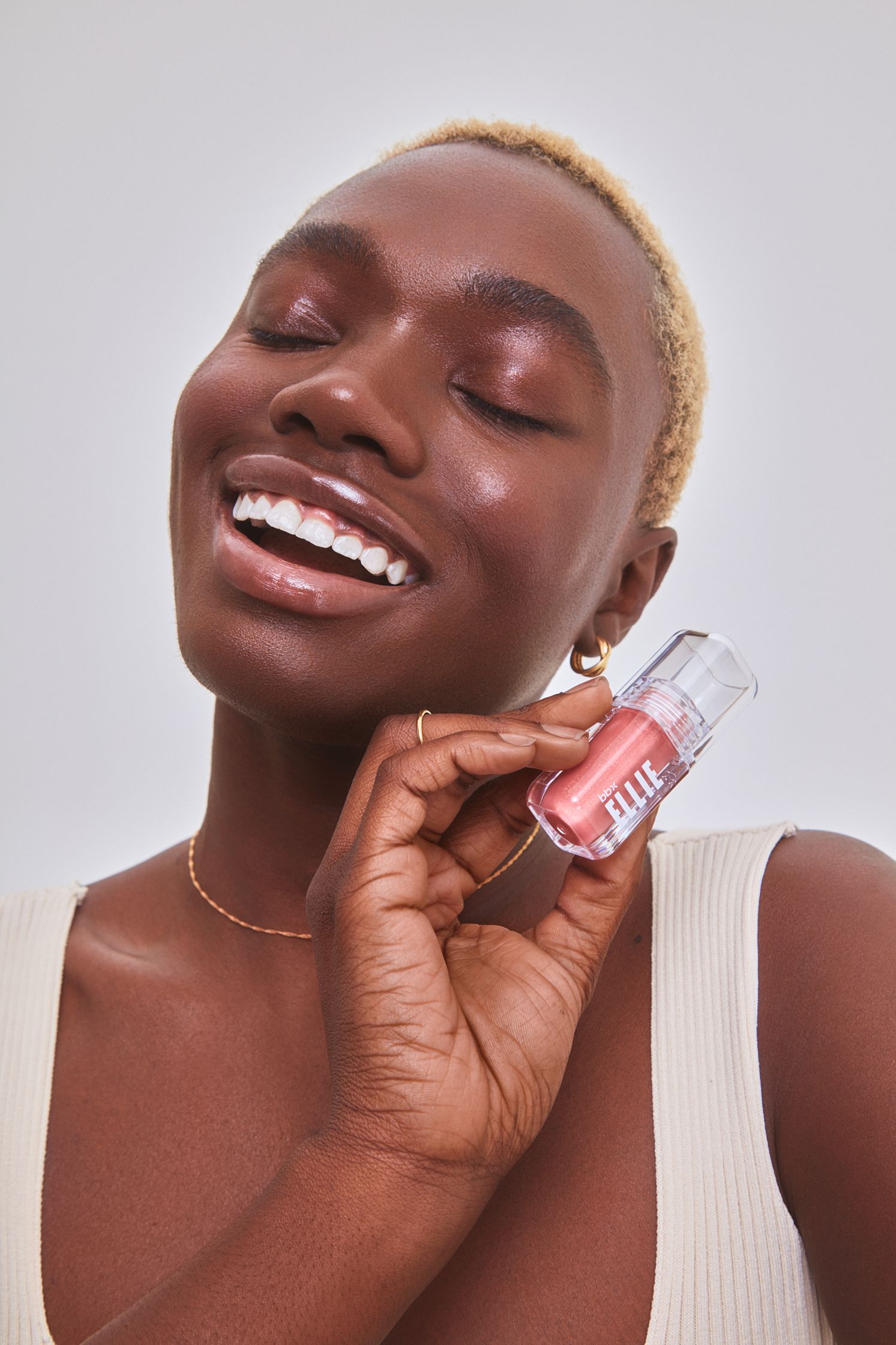 a woman is smiling while holding a pink lipstick