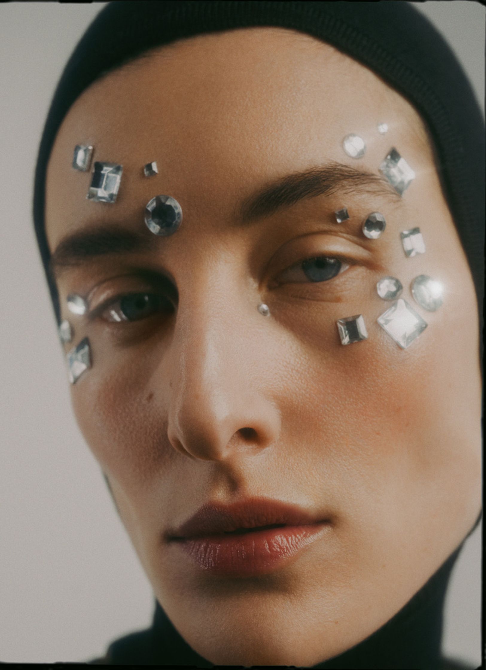 a woman wearing a black hat with silver studs on her face