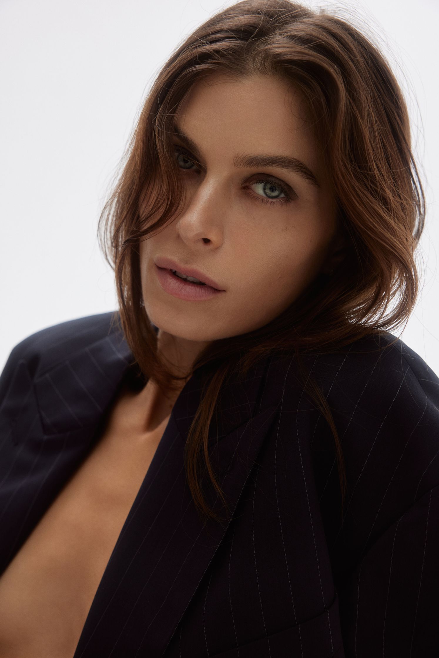 a woman in a black suit posing in front of a white background