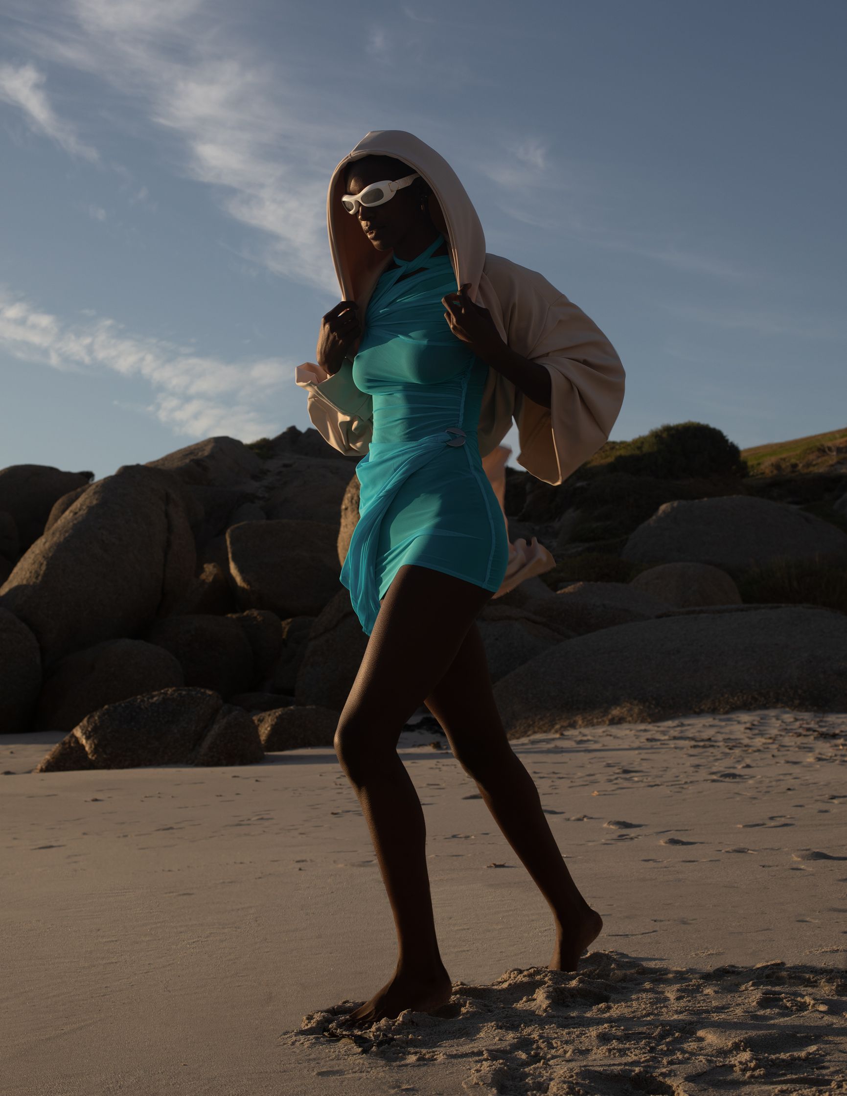 a woman in a blue dress walking on the beach