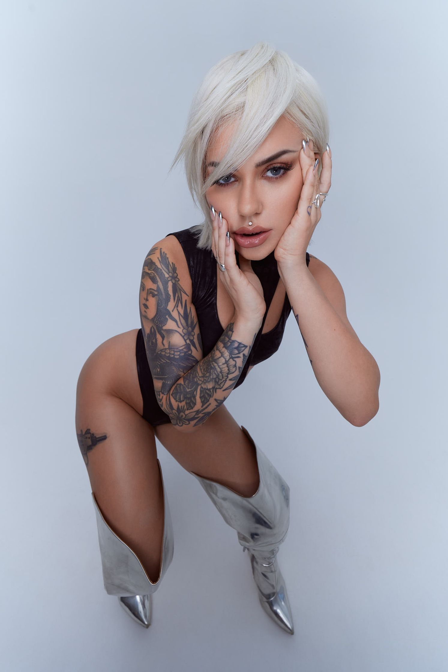 a woman with white hair and tattoos posing on a white background