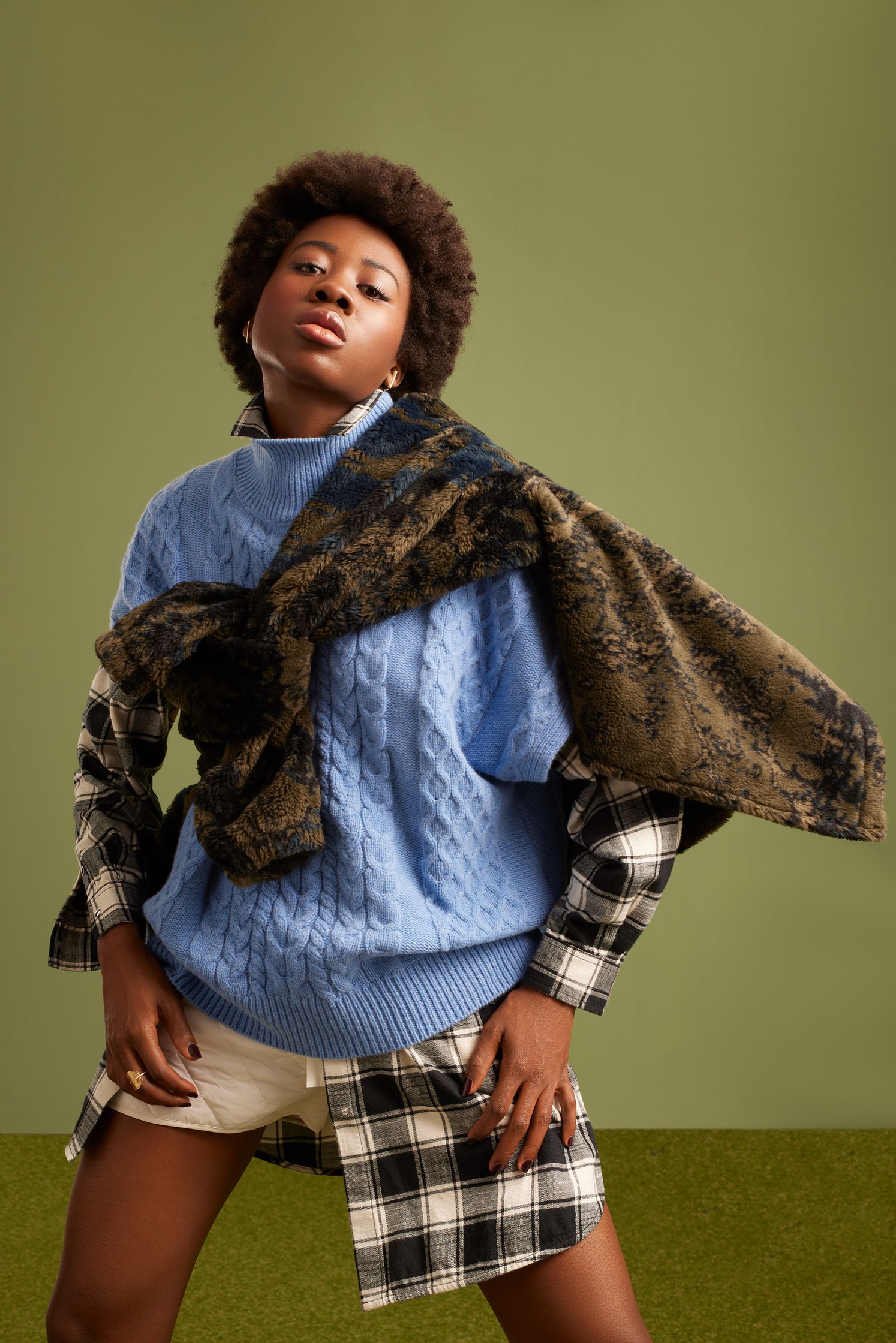 a black woman wearing a blue sweater and plaid scarf