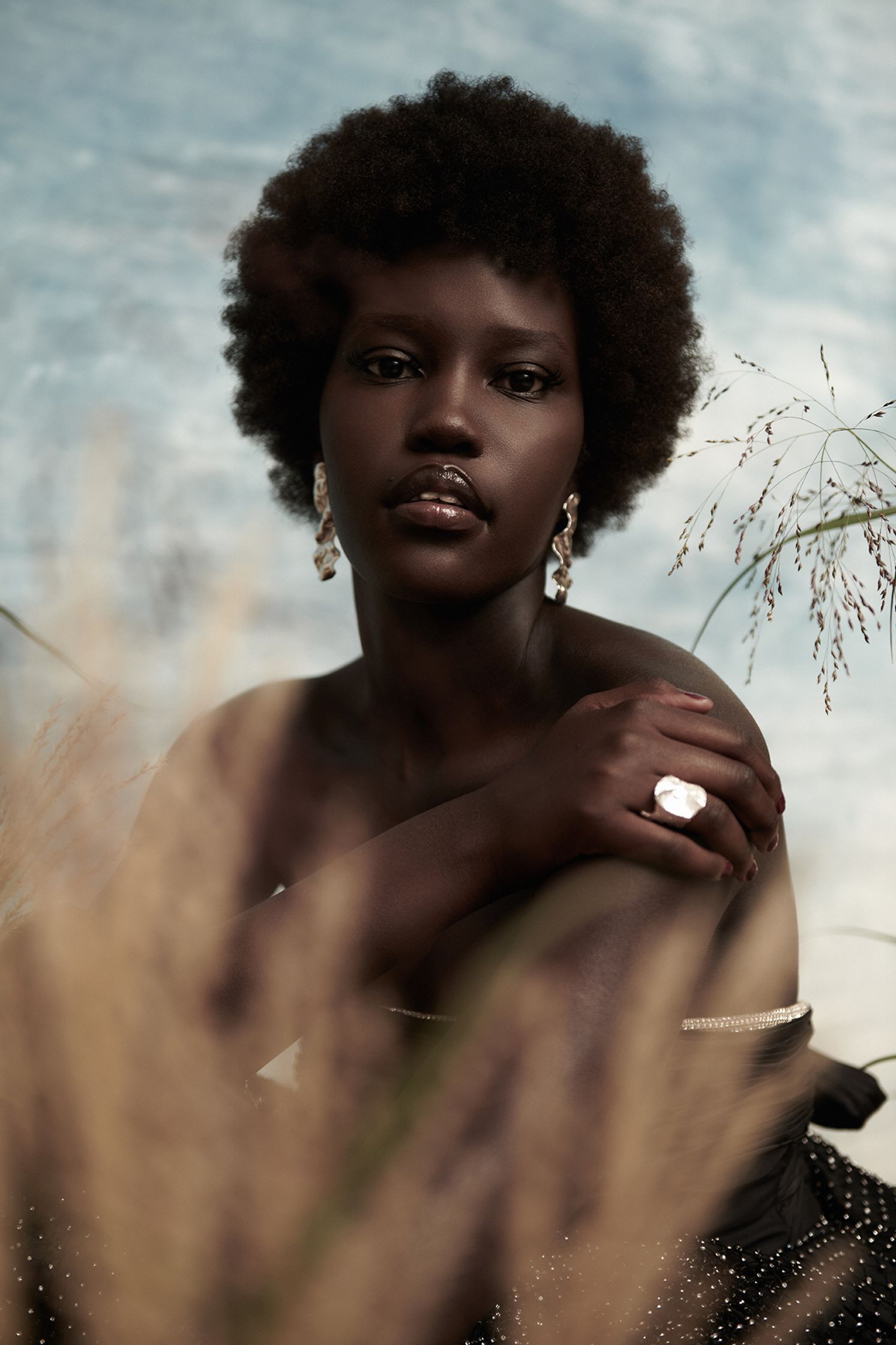 a black woman in a dress sitting in tall grass
