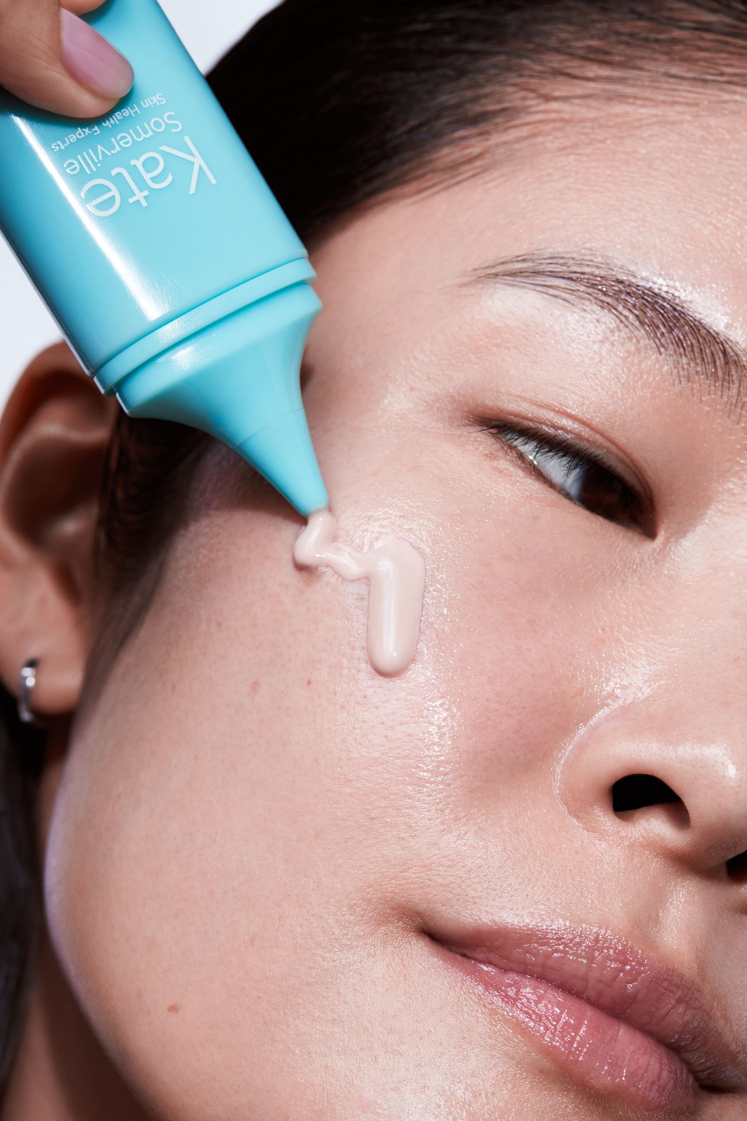 a woman is applying a cream to her face