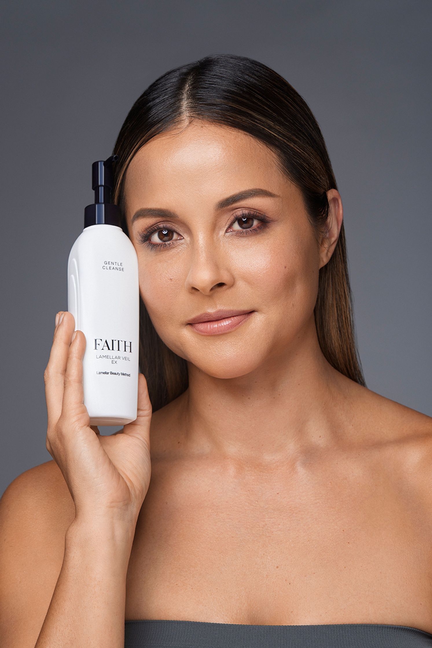 a woman holding a bottle of facial cleanser