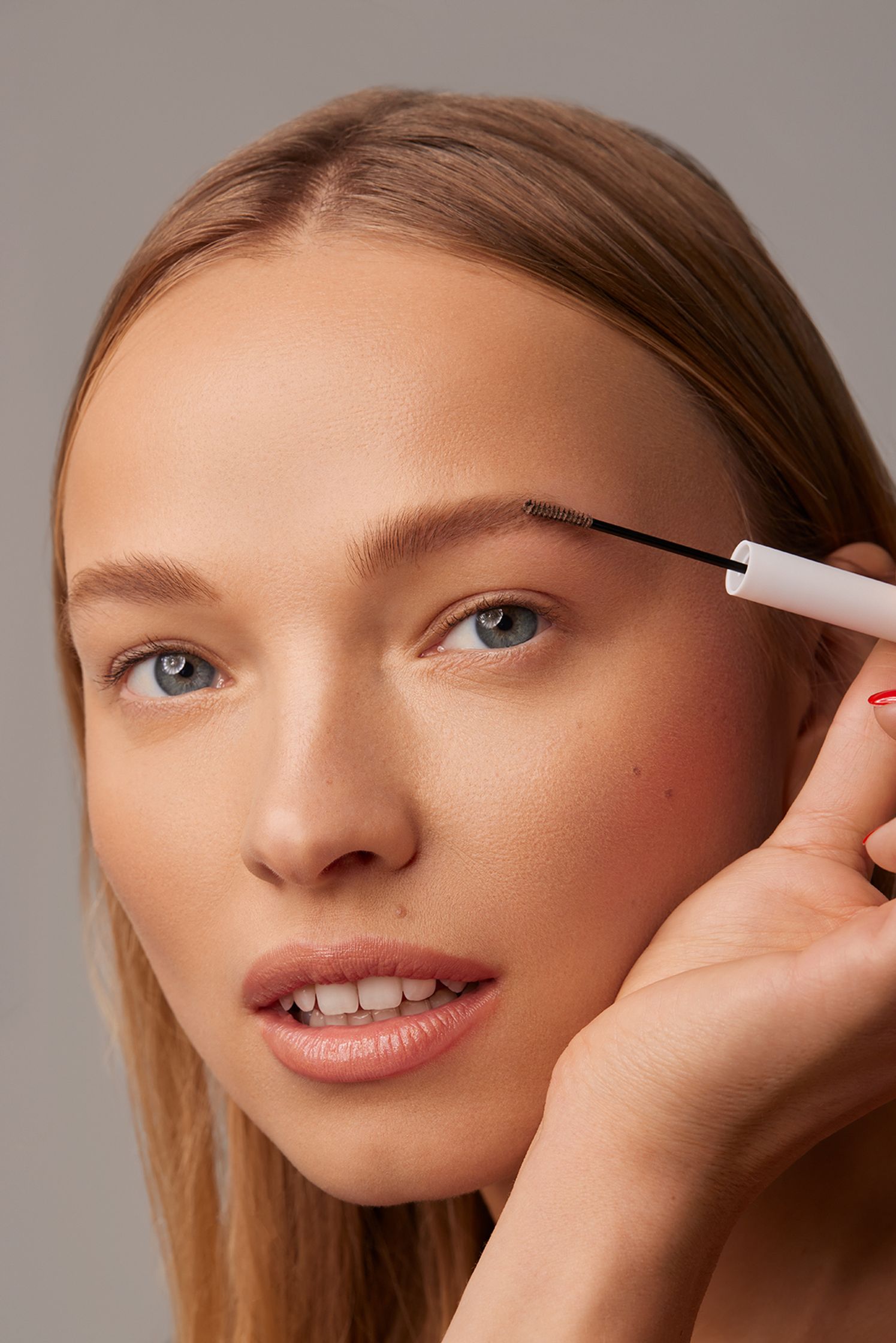 a woman is putting mascara on her eyebrows