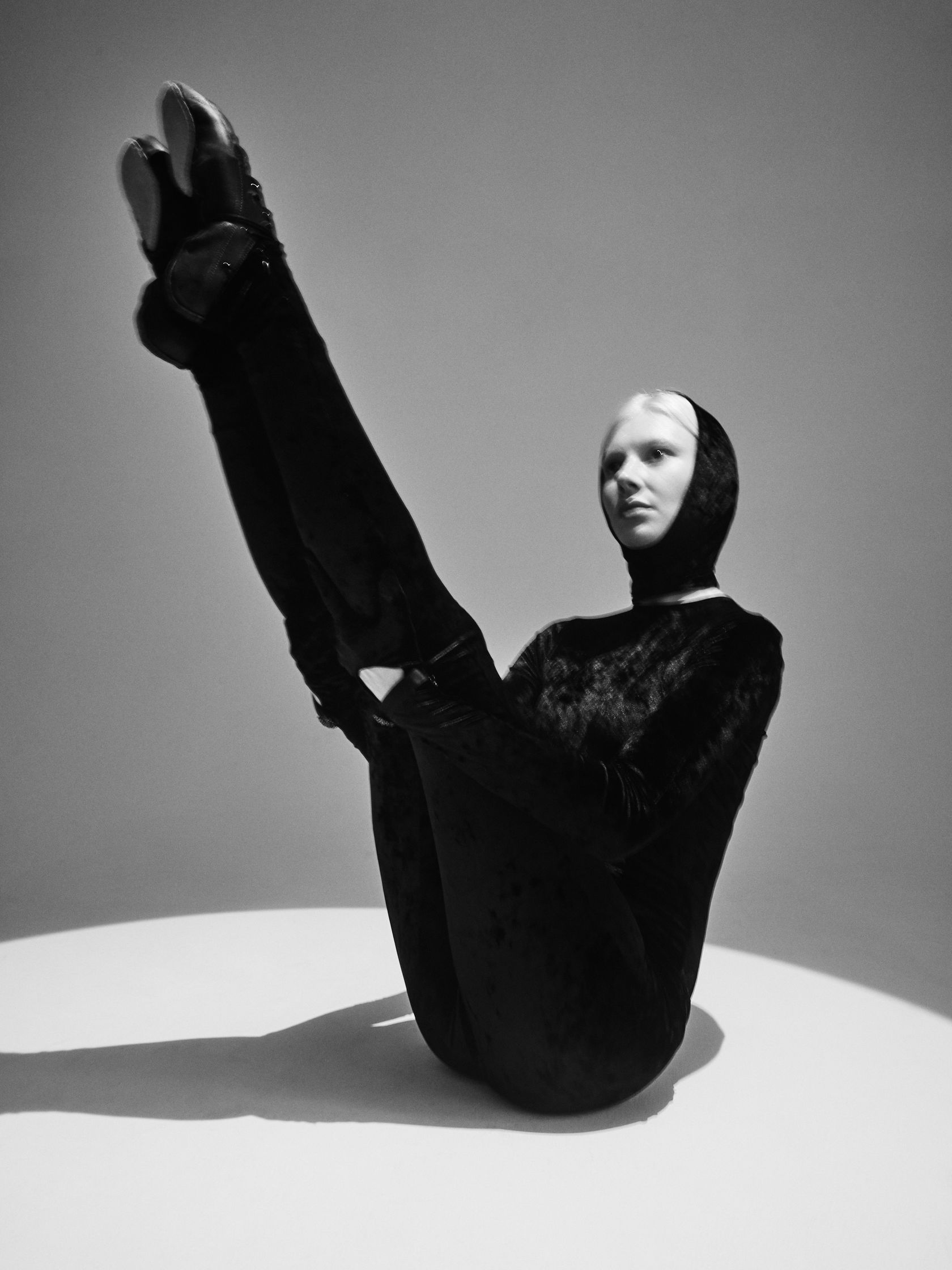 a black and white photo of a woman in a black outfit