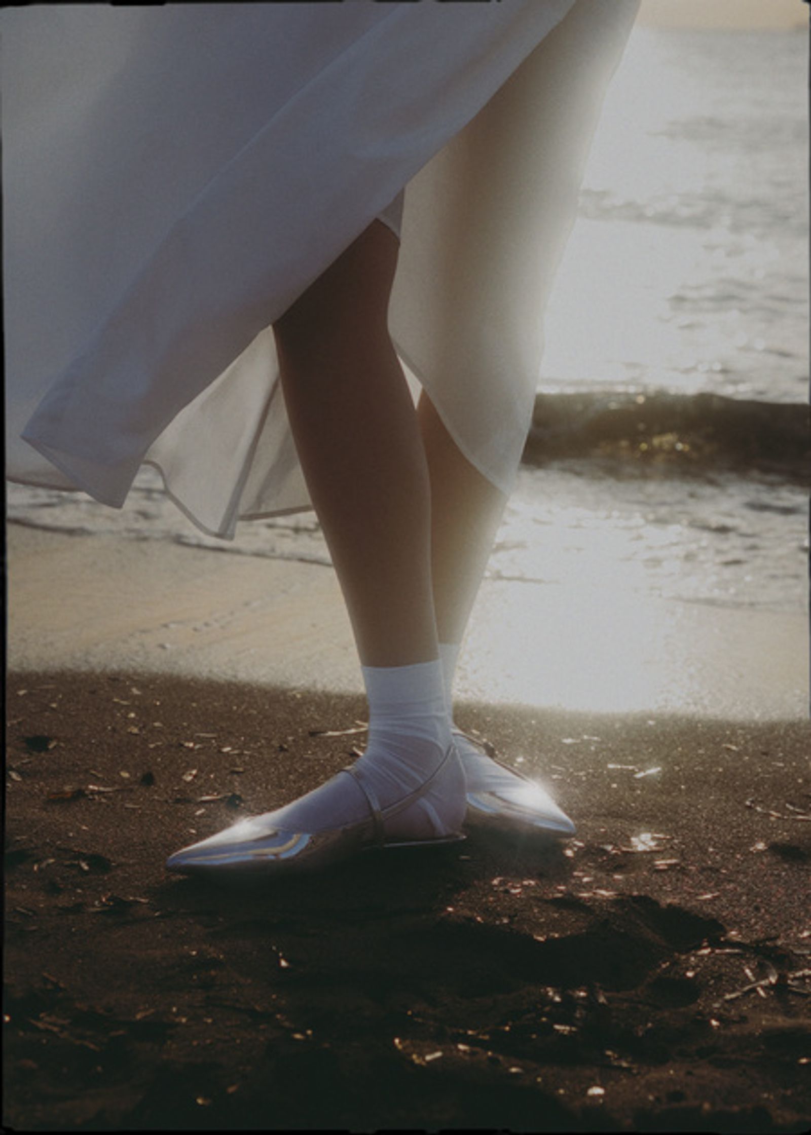 a woman in a white dress standing on the beach