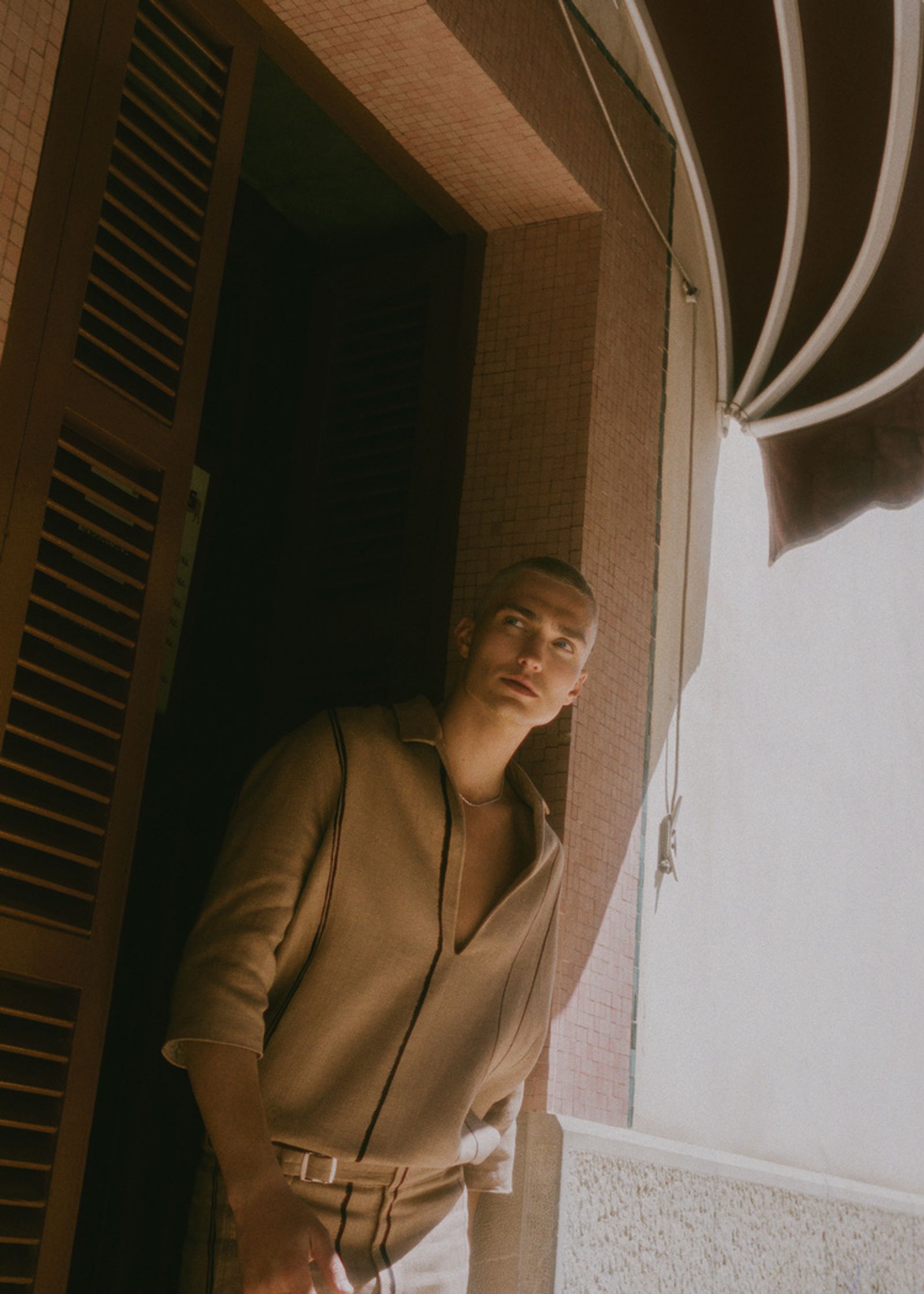 a man in a tan suit standing in front of a door