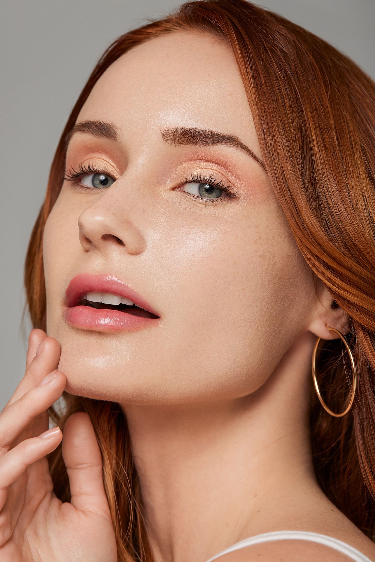 a woman with red hair is posing with a hoop earring