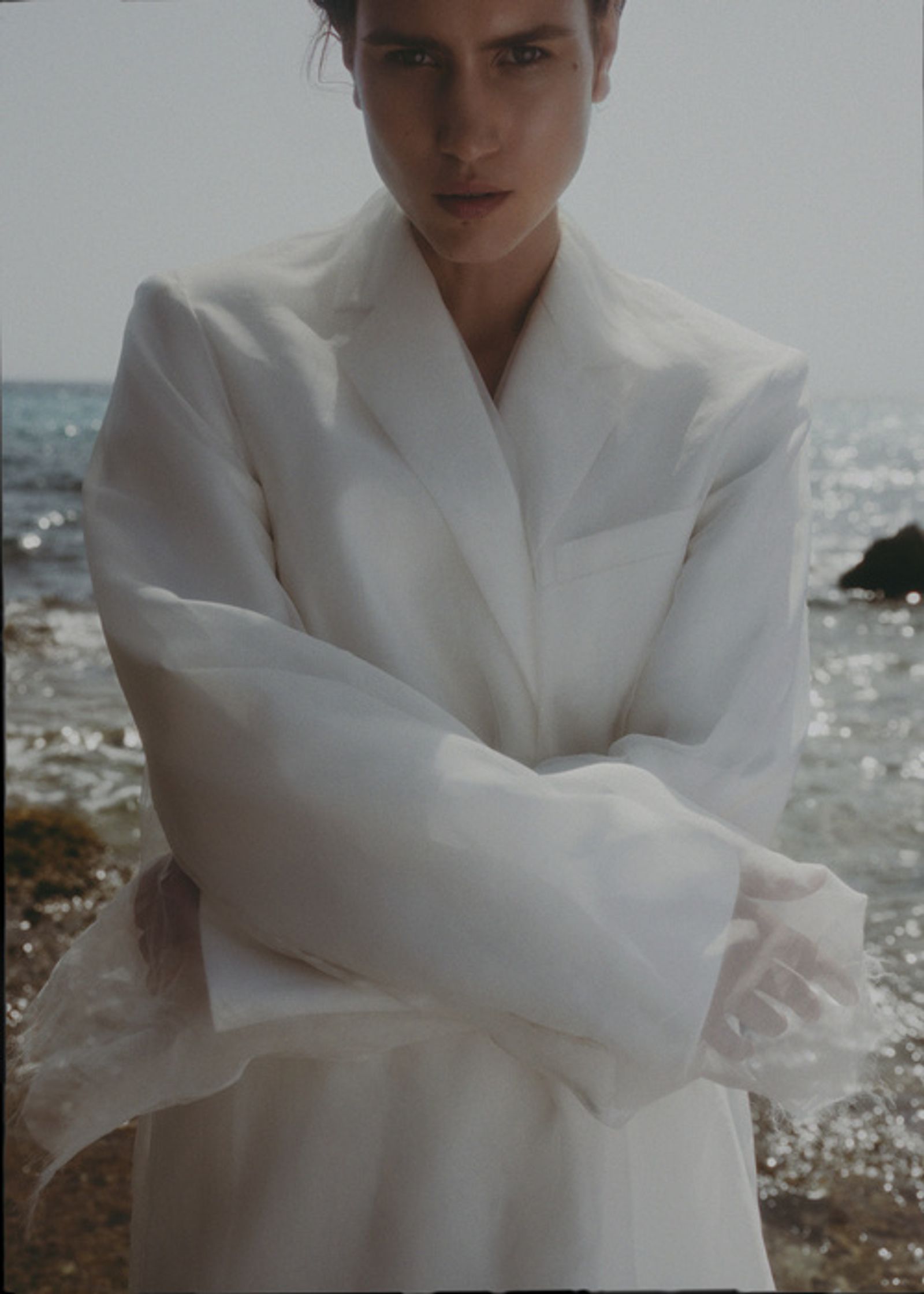 a woman in a white coat standing on the beach