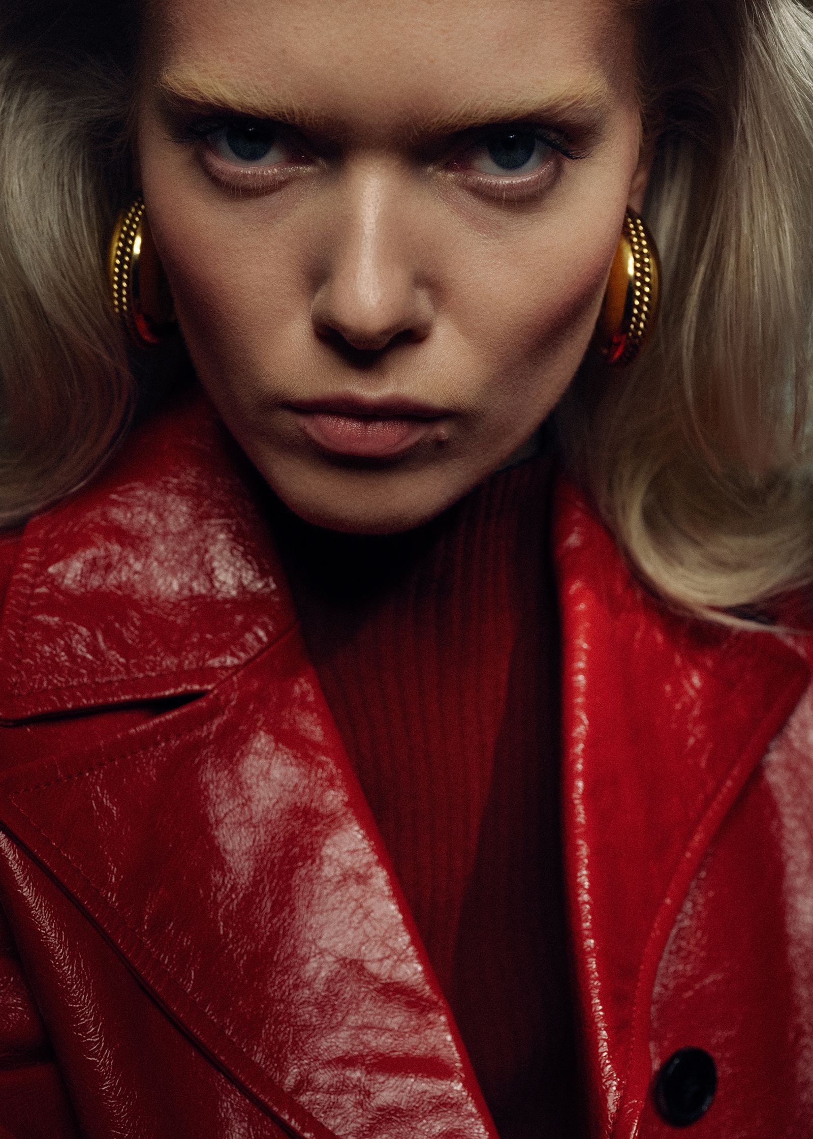 a woman in a red leather jacket with hoop earrings