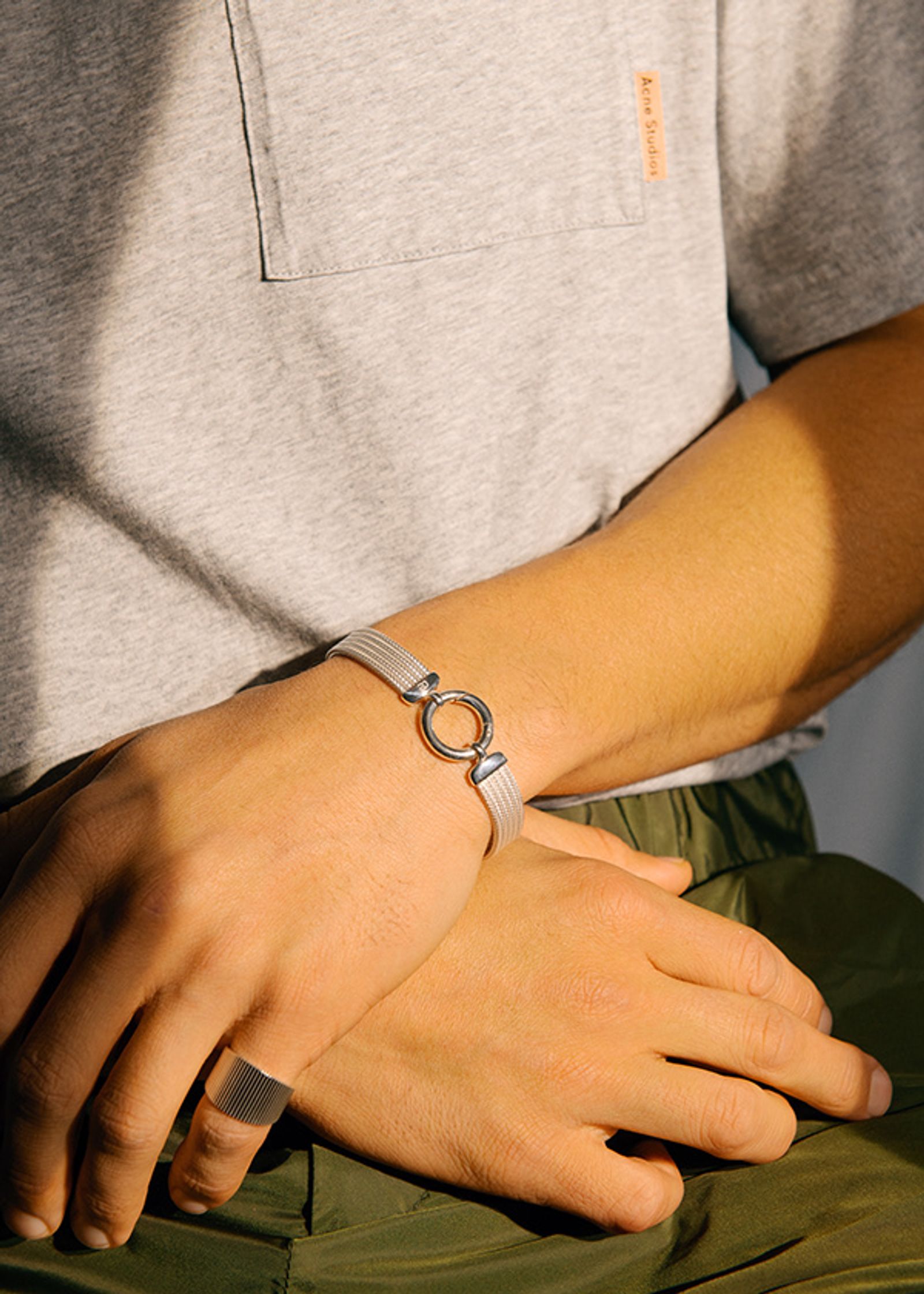 a man wearing a grey shirt and a silver bracelet