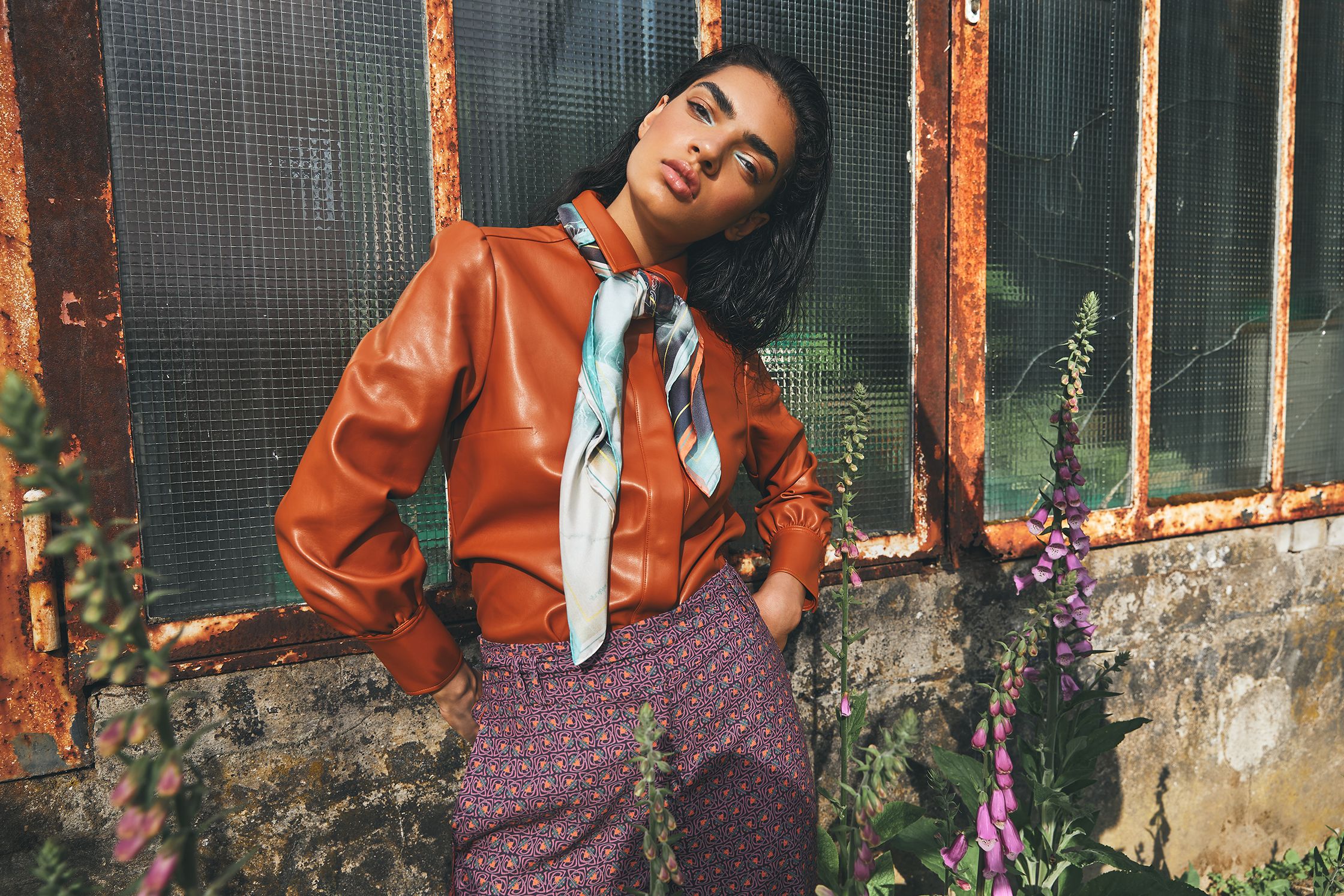 a woman wearing a brown leather shirt and purple pants