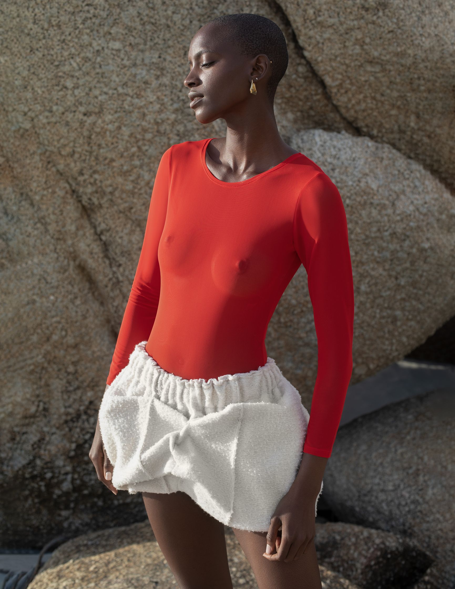 a black woman in a red bodysuit and white skirt