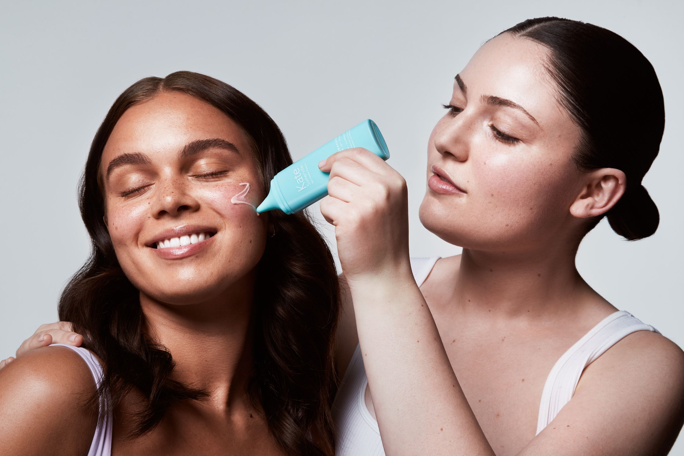a woman is using a facial brush to clean her face