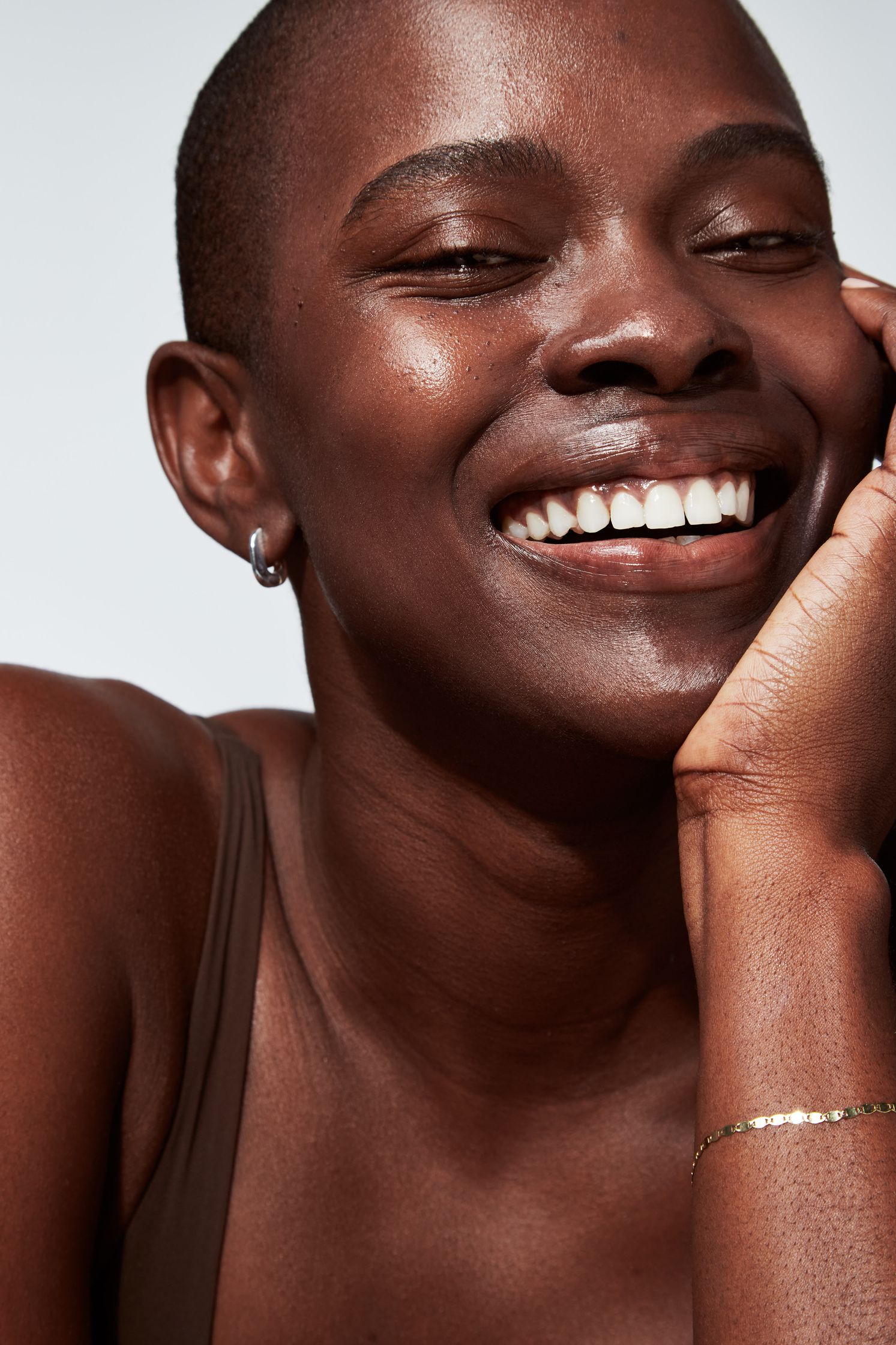 a black woman smiling with her hands on her face
