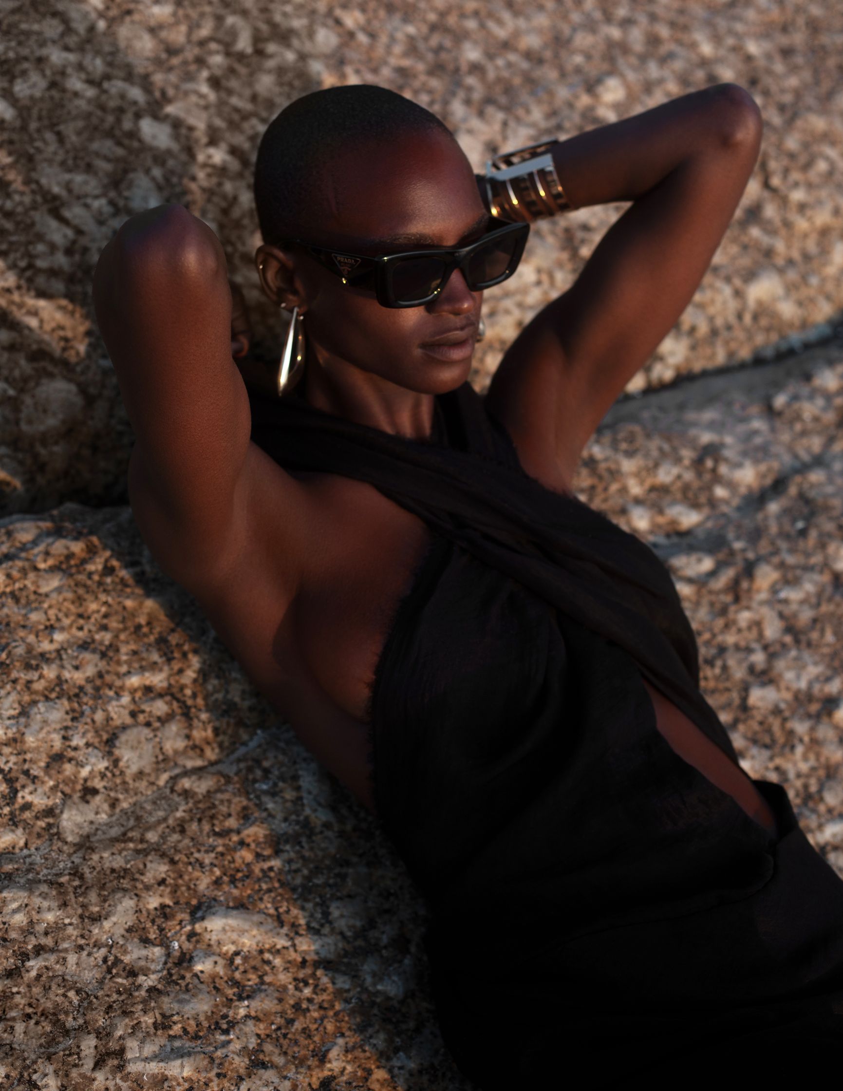 a woman in a black dress laying on a rock