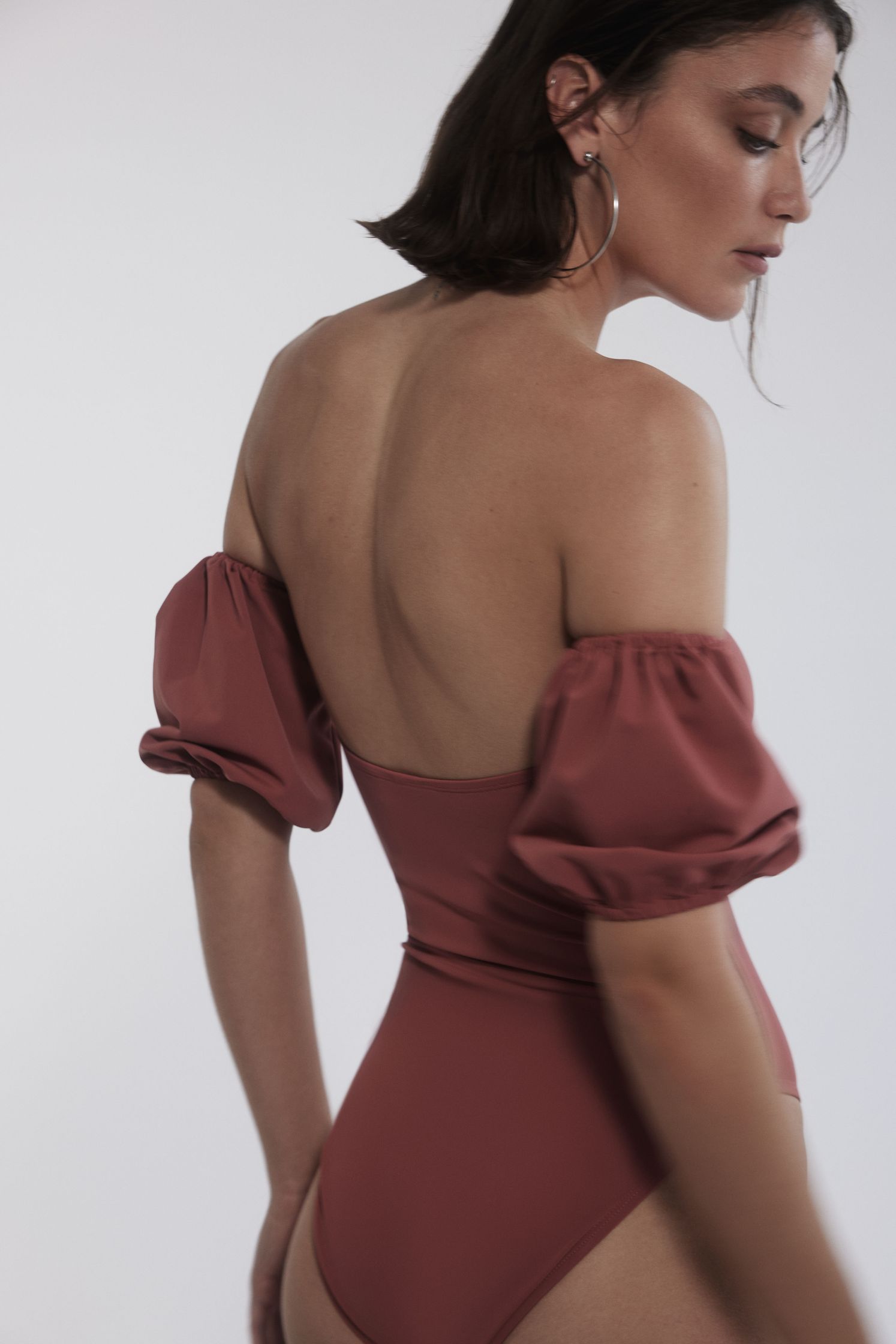 the back view of a woman wearing a pink off shoulder swimsuit
