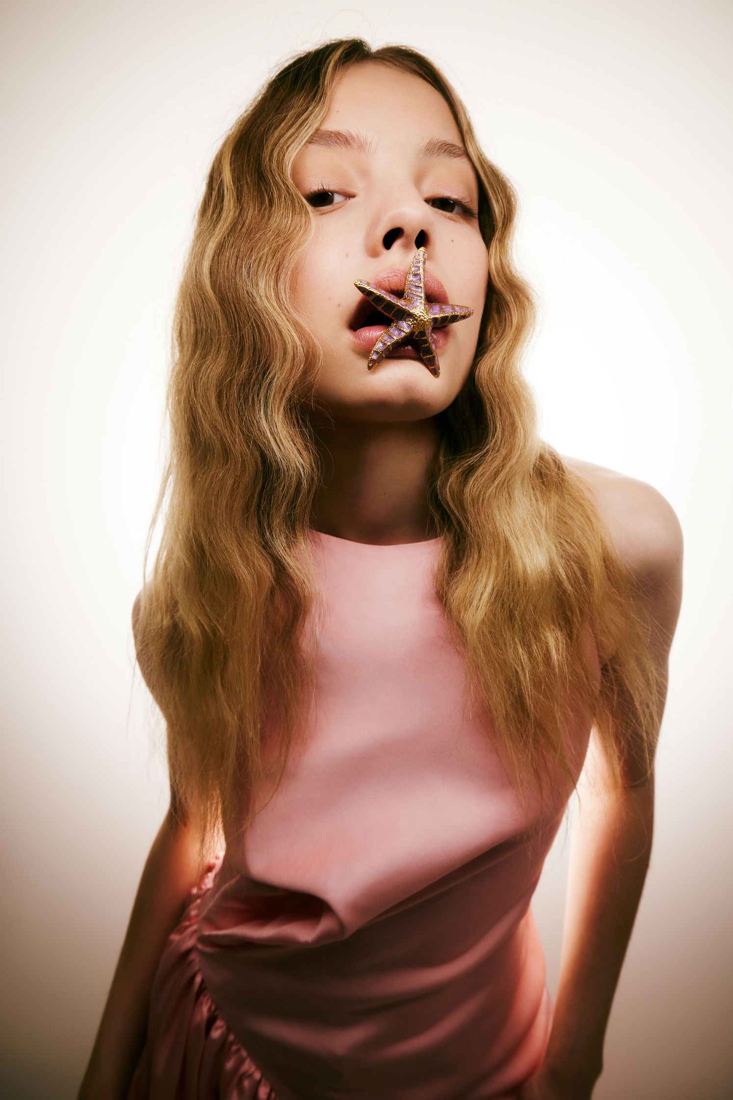a girl with long hair is posing with a toothpick in her mouth